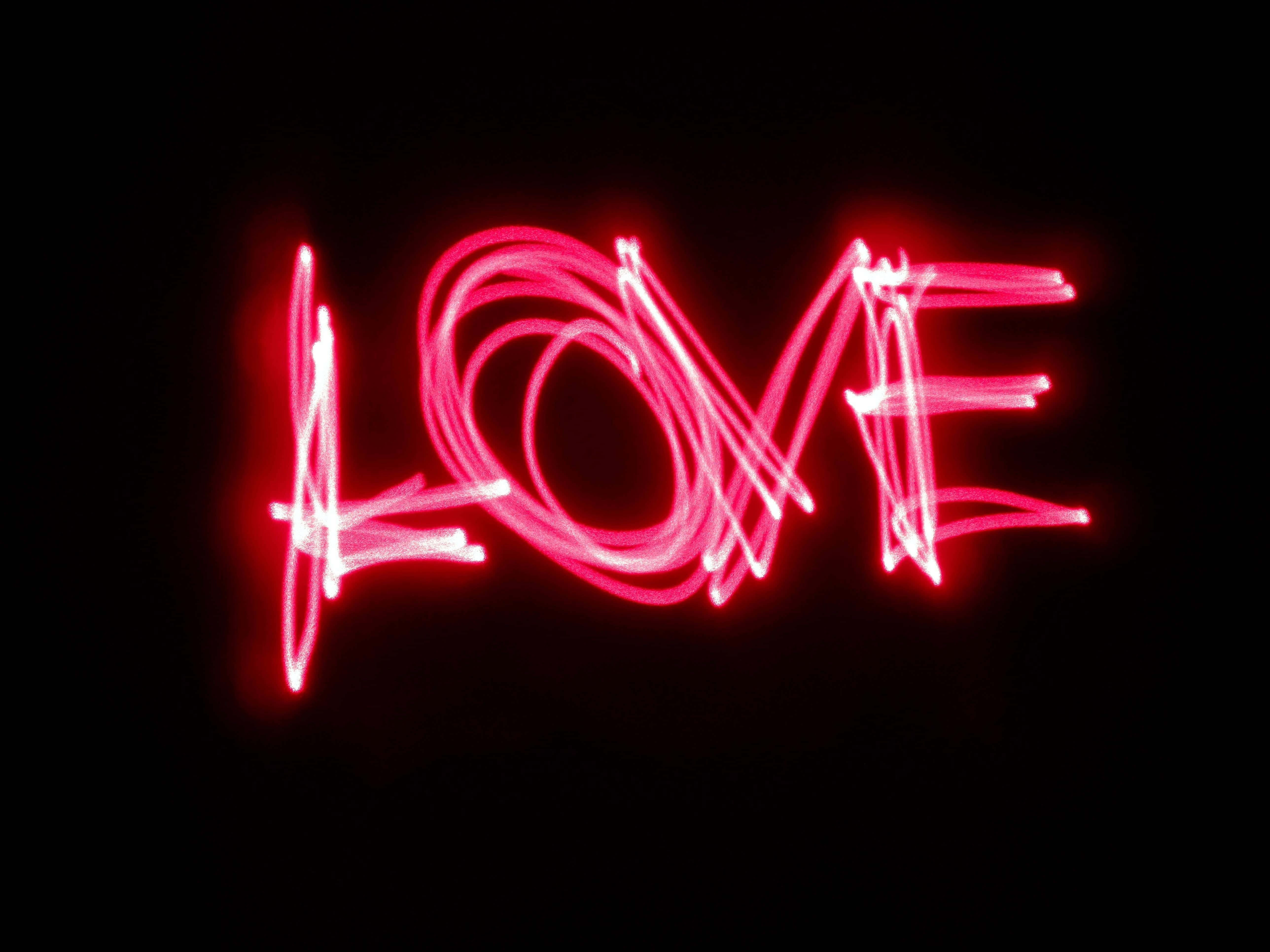 Red Led 桌布 壁紙 — 鮮豔的紅色光軌在漆黑的背景上以動態手寫風格拼出LOVE這個詞。
