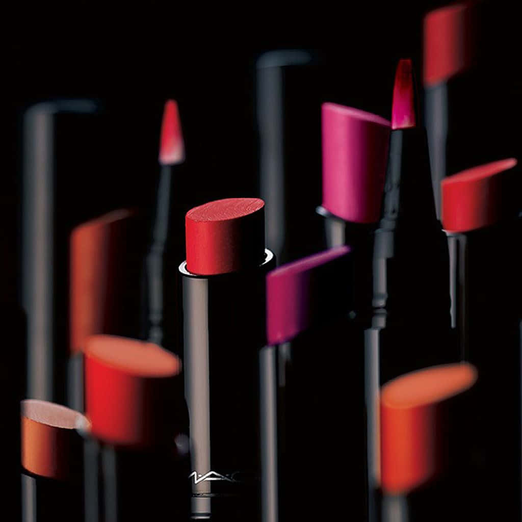Mac Cosmetics 桌布 壁紙 — 鮮豔的紅色和粉紅色唇膏以淺景深排列在黑色背景上。