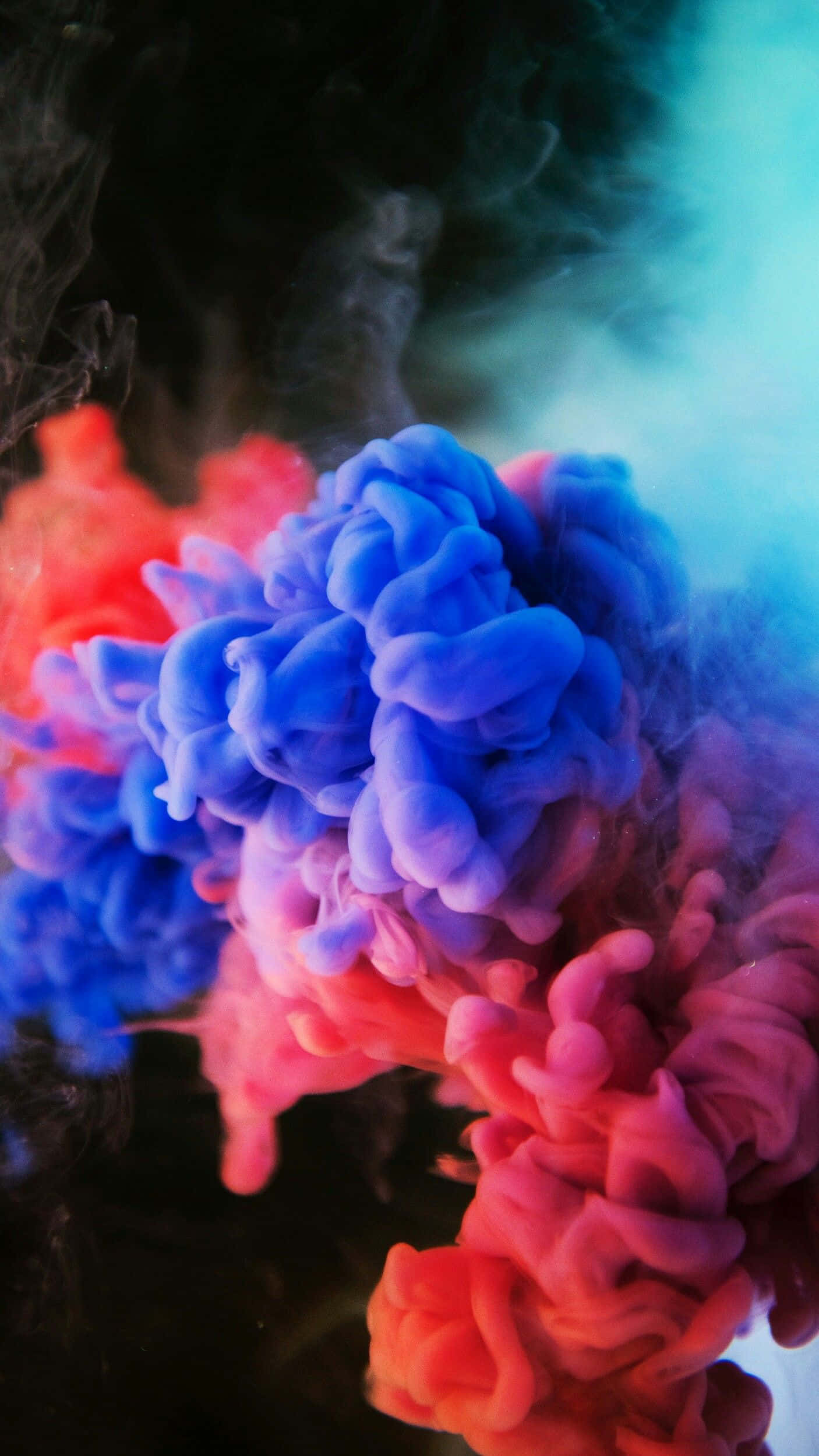 Color Smoke 桌布 壁紙 — 鮮豔的紅色和藍色墨水在水中旋轉混合，形成動態的抽象色彩爆炸。
