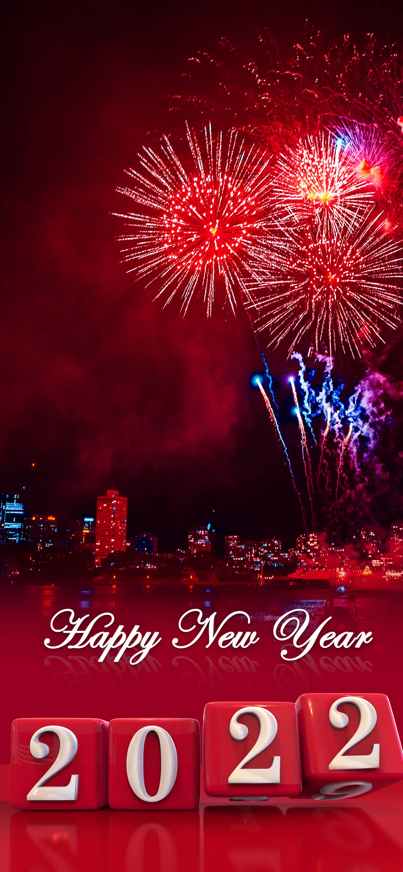 Happy New Year 2022 桌布 壁紙 — 鮮豔的紅色和藍色煙火在城市天際線上爆炸，'Happy New Year 2022' 方塊在反光表面上閃耀。