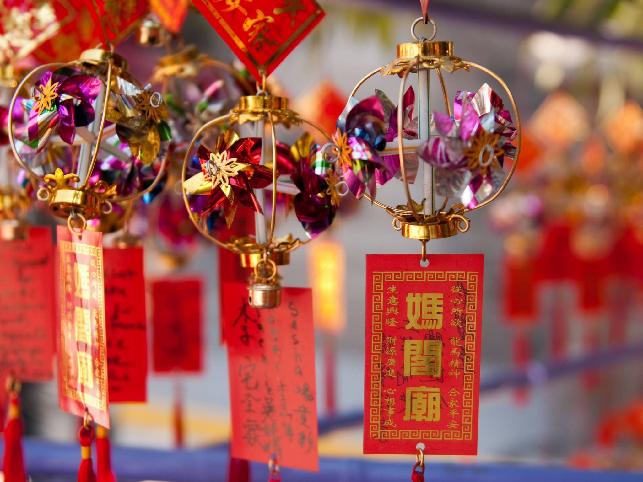 中文 桌布 壁紙 — 鮮豔的紅色和金色紙燈籠帶有精緻的花卉圖案，懸掛在節日氣氛的寺廟中。