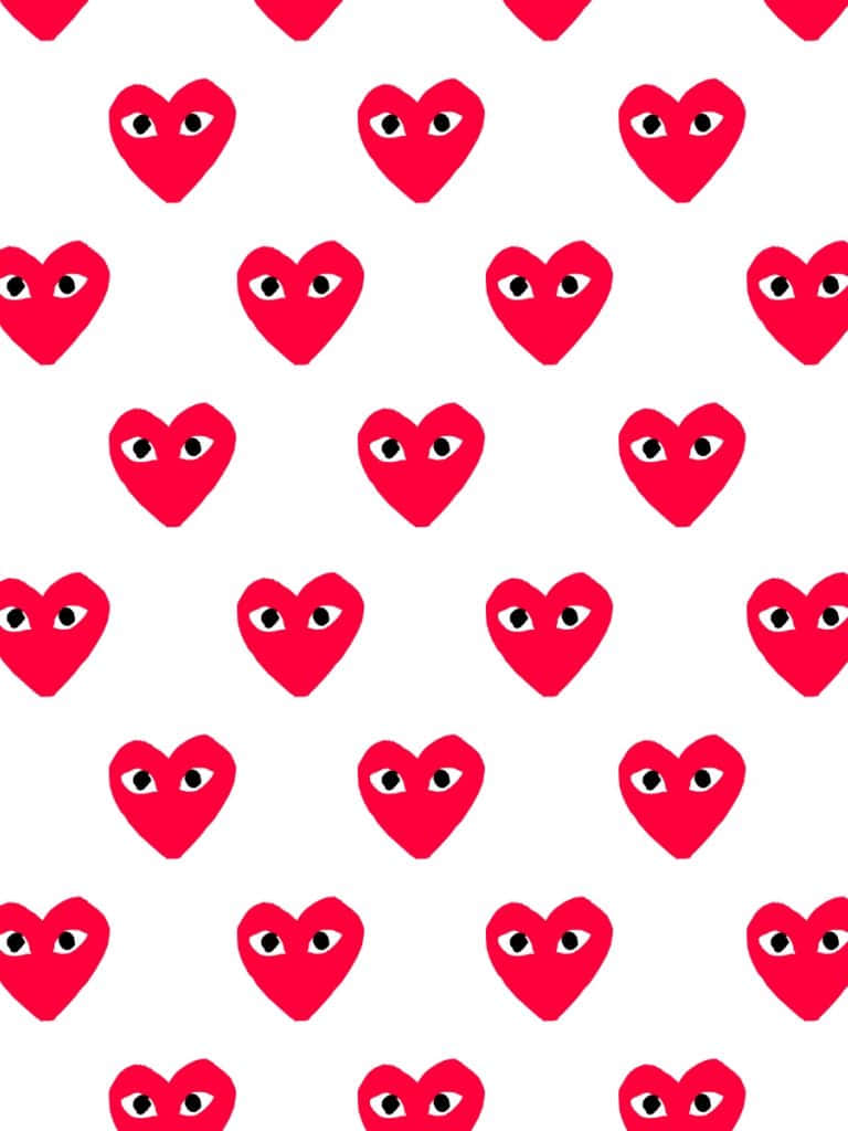 cdg 桌布 壁紙 — 鮮豔的紅色心形圖案帶有黑色眼睛，在純白背景上以網格重複排列，形成大膽的圖形圖案。