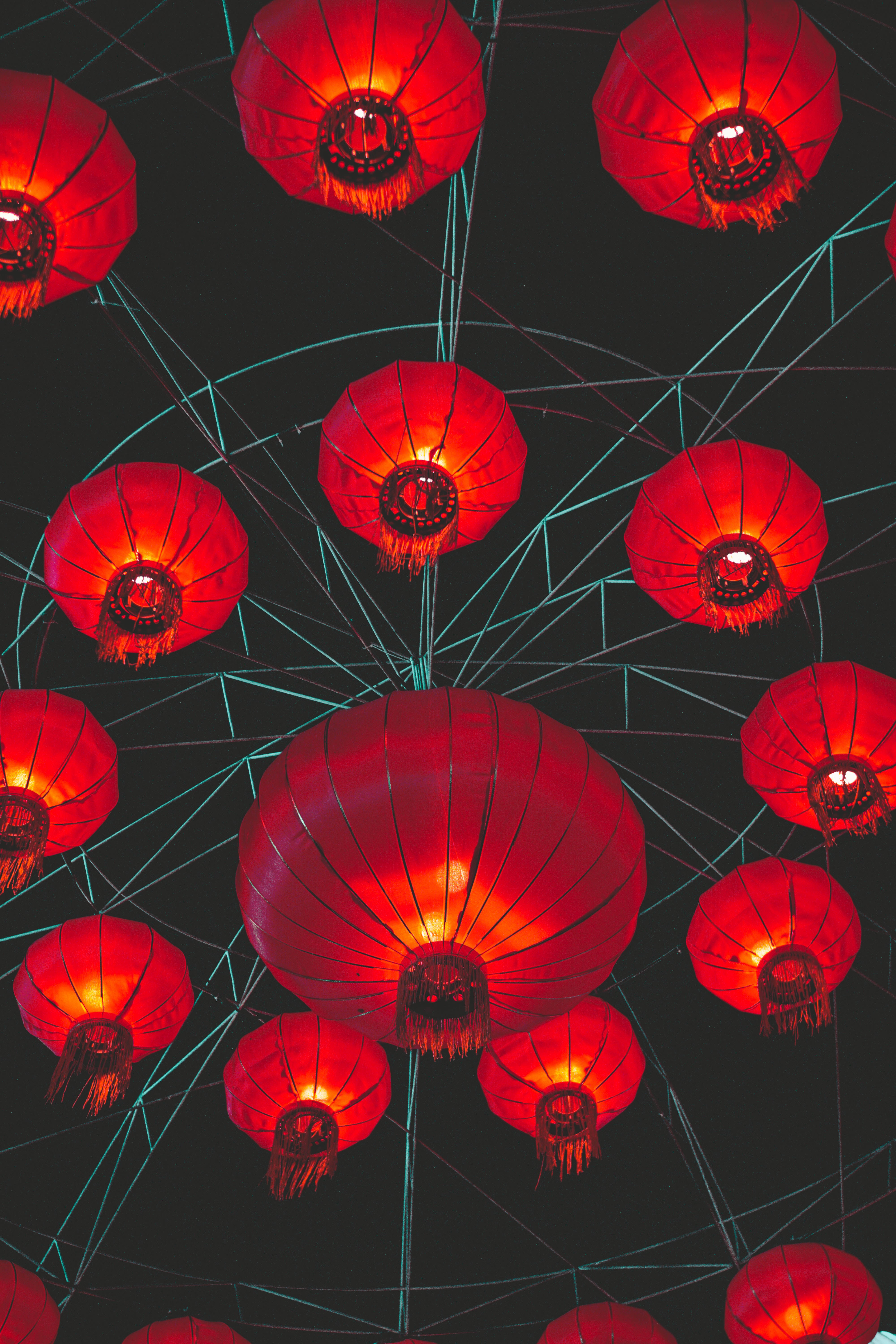 中文 桌布 壁紙 — 鮮豔的紅色燈籠在由發光青綠色電線編織而成的黑暗天花板上溫暖地發光。