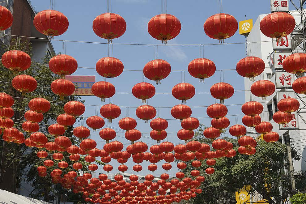 春節 桌布 壁紙 — 鮮豔的紅色燈籠密密麻麻地掛在繁華街道上方，襯著晴朗的藍天。