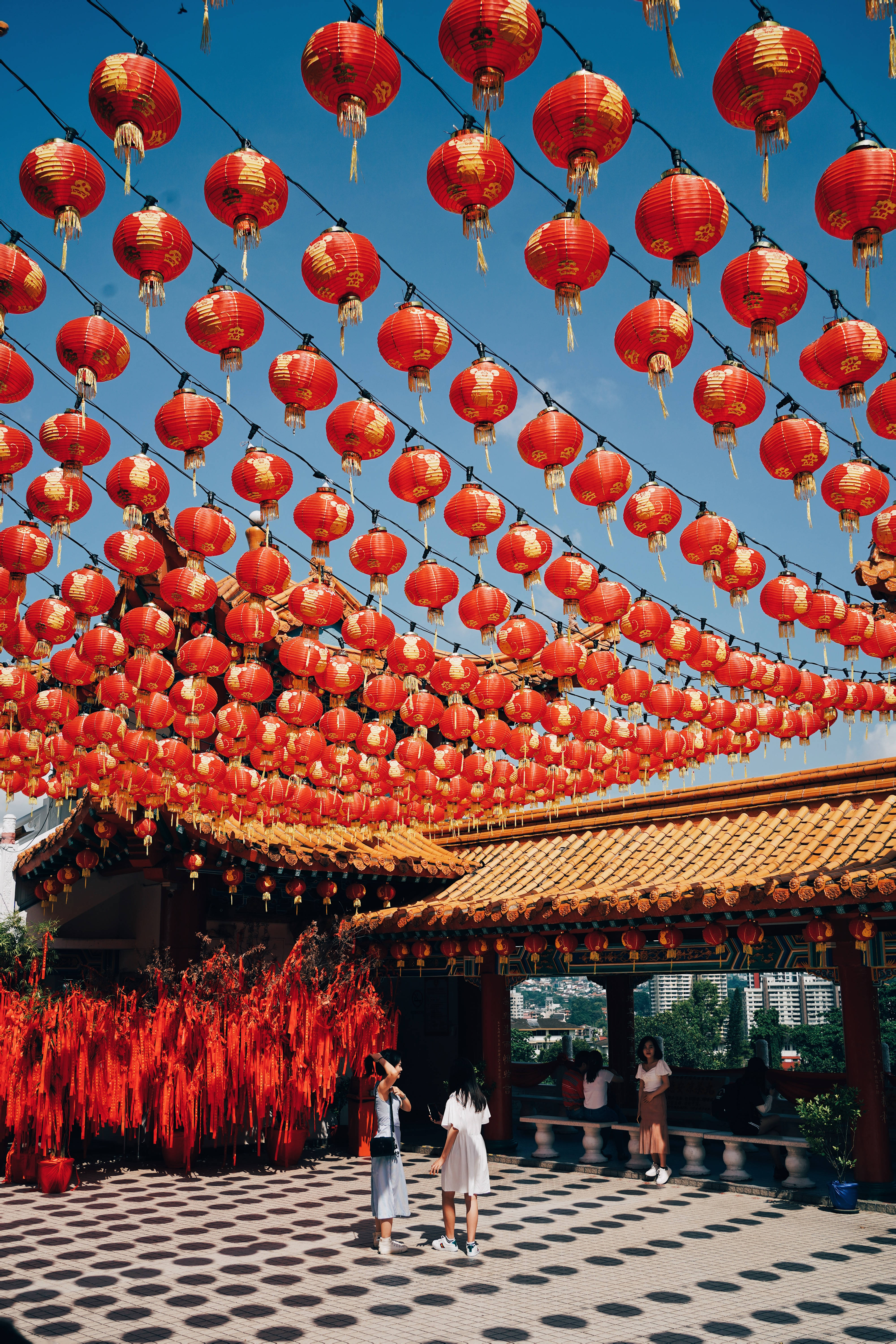 春節 桌布 壁紙 — 鮮豔的紅色燈籠密密麻麻地掛在頭頂上方，襯著清澈的藍天，下方是傳統的瓦頂亭閣。
