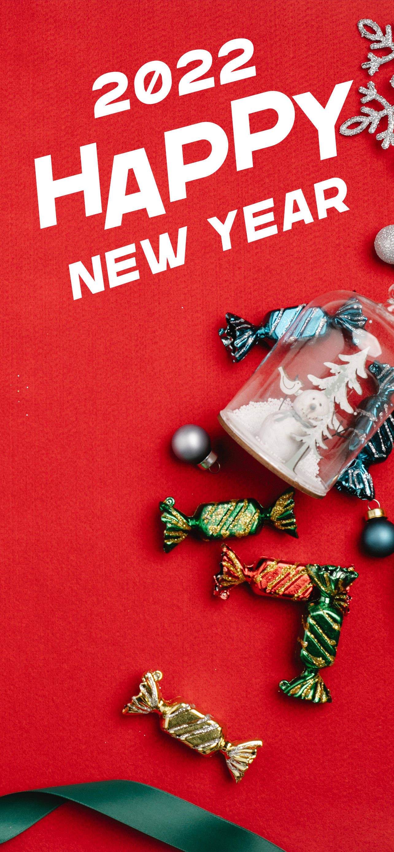 Happy New Year 2022 桌布 壁紙 — 鮮豔的紅色背景，粗體白色文字寫著 2022 HAPPY NEW YEAR，周圍環繞著節日糖果、裝飾品和一個雪球。