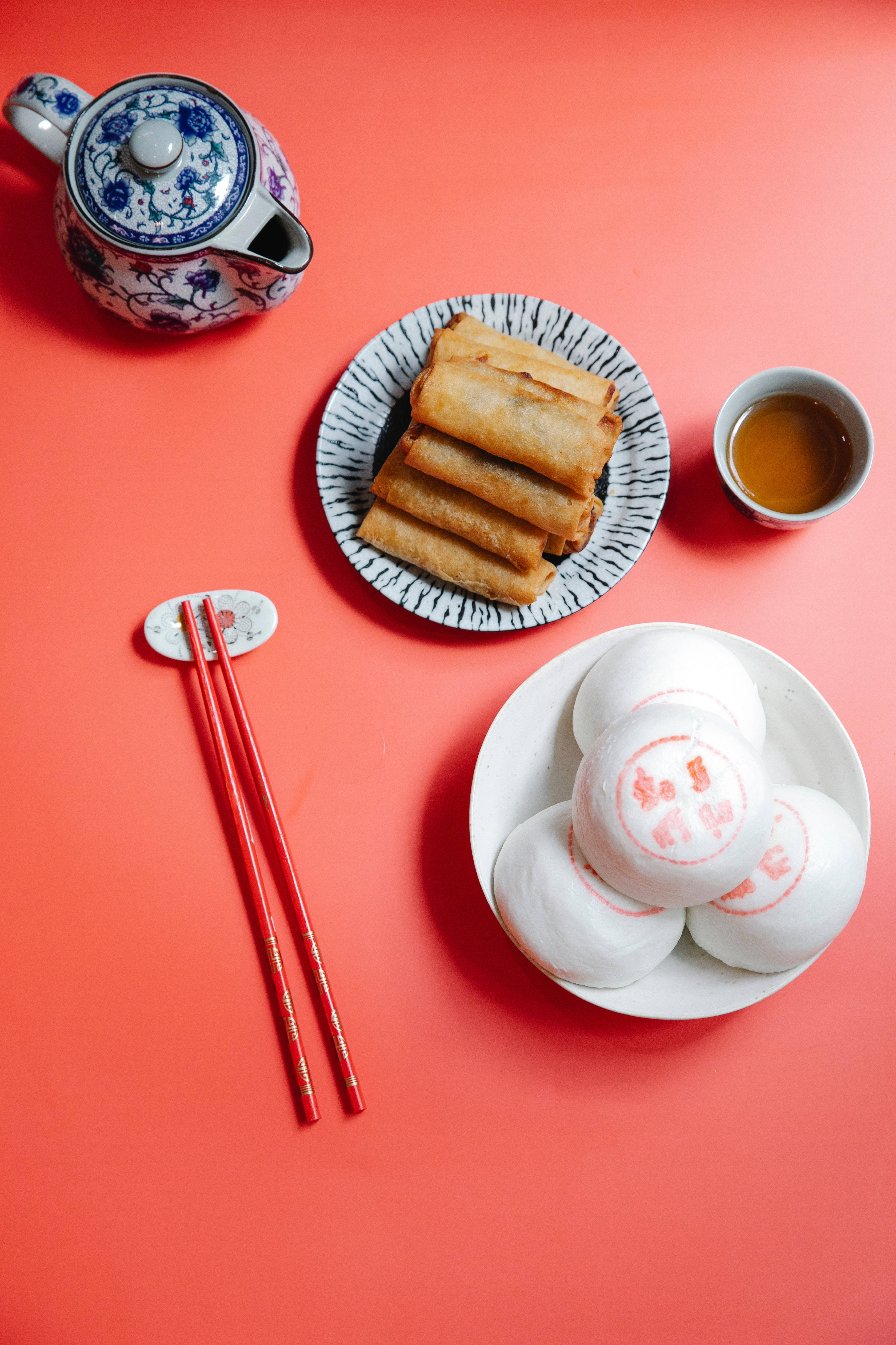 Egg 桌布 壁紙 — 鮮豔的紅色表面上展示著傳統中式茶具和餃子，搭配金黃色的春捲。