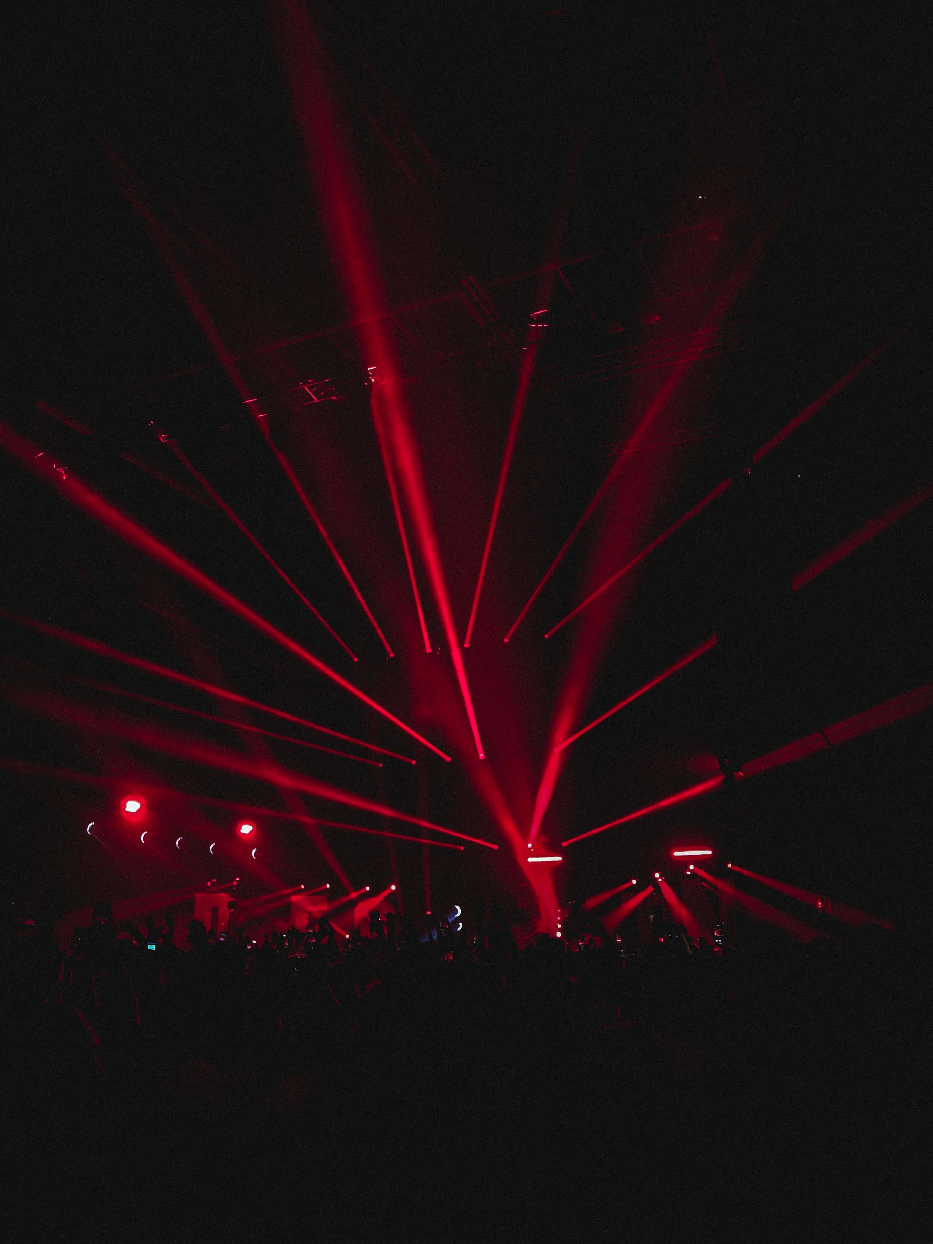 Laser 桌布 壁紙 — 鮮豔的紅色雷射光束從黑暗的舞台射向剪影人群上方的夜空。
