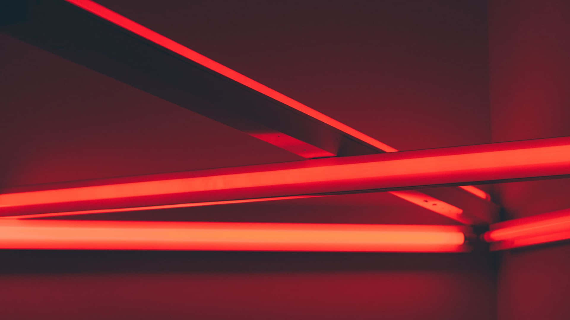 Aesthetic Red 桌布 壁紙 — 鮮豔的紅色霓虹管在極簡室內環境中，於深色牆壁上發光。