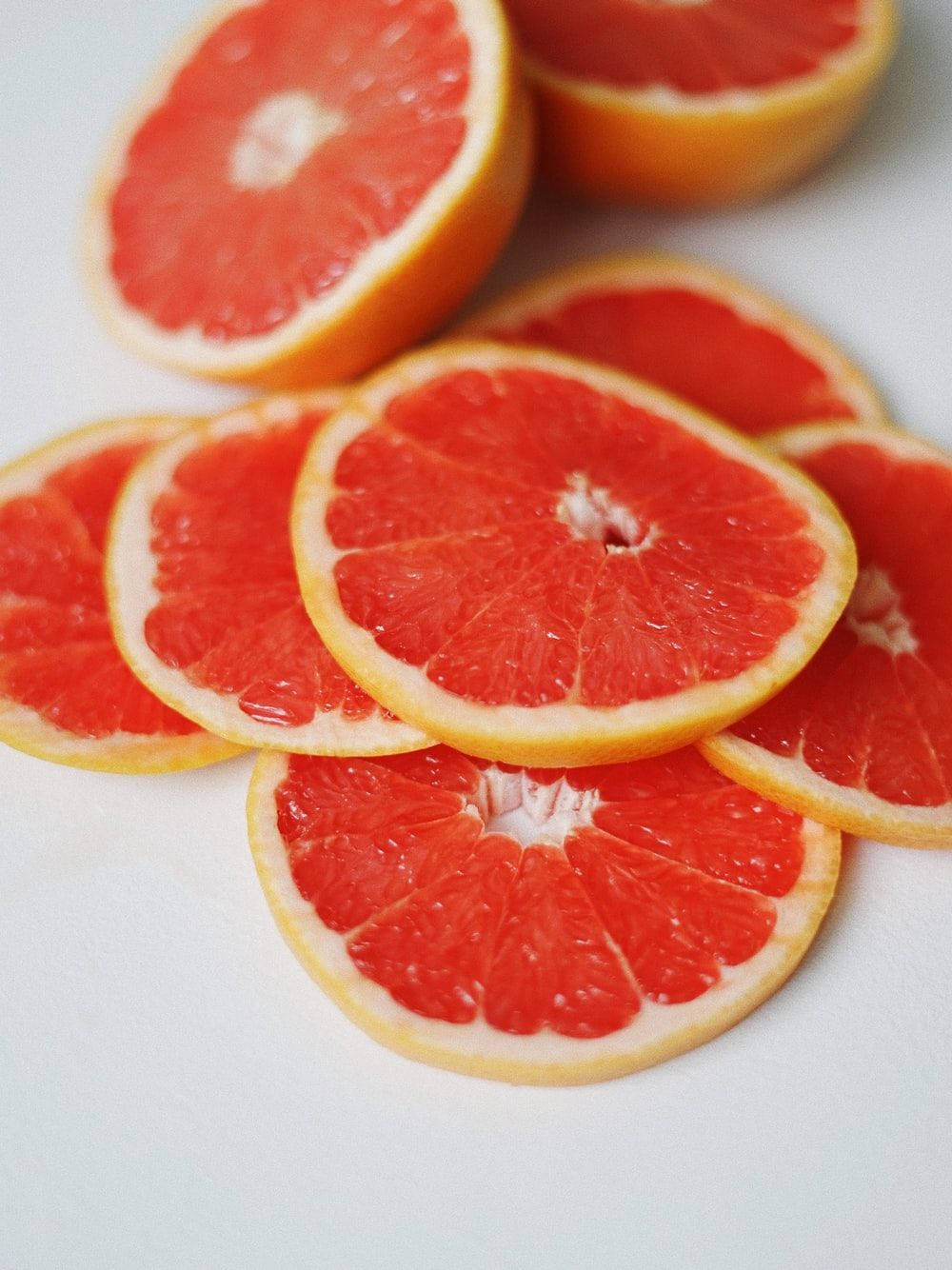 Grapefruit 桌布 壁紙 — 鮮豔的紅葡萄柚切片整齊排列在潔白的表面上，展現多汁的果肉和光亮的果皮。