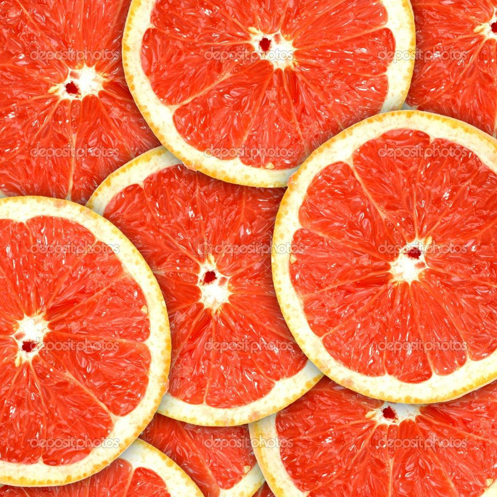 Fruits 桌布 壁紙 — 鮮豔的紅葡萄柚片以緊密重疊的圖案排列，展示多汁的果肉和紋理豐富的果皮。