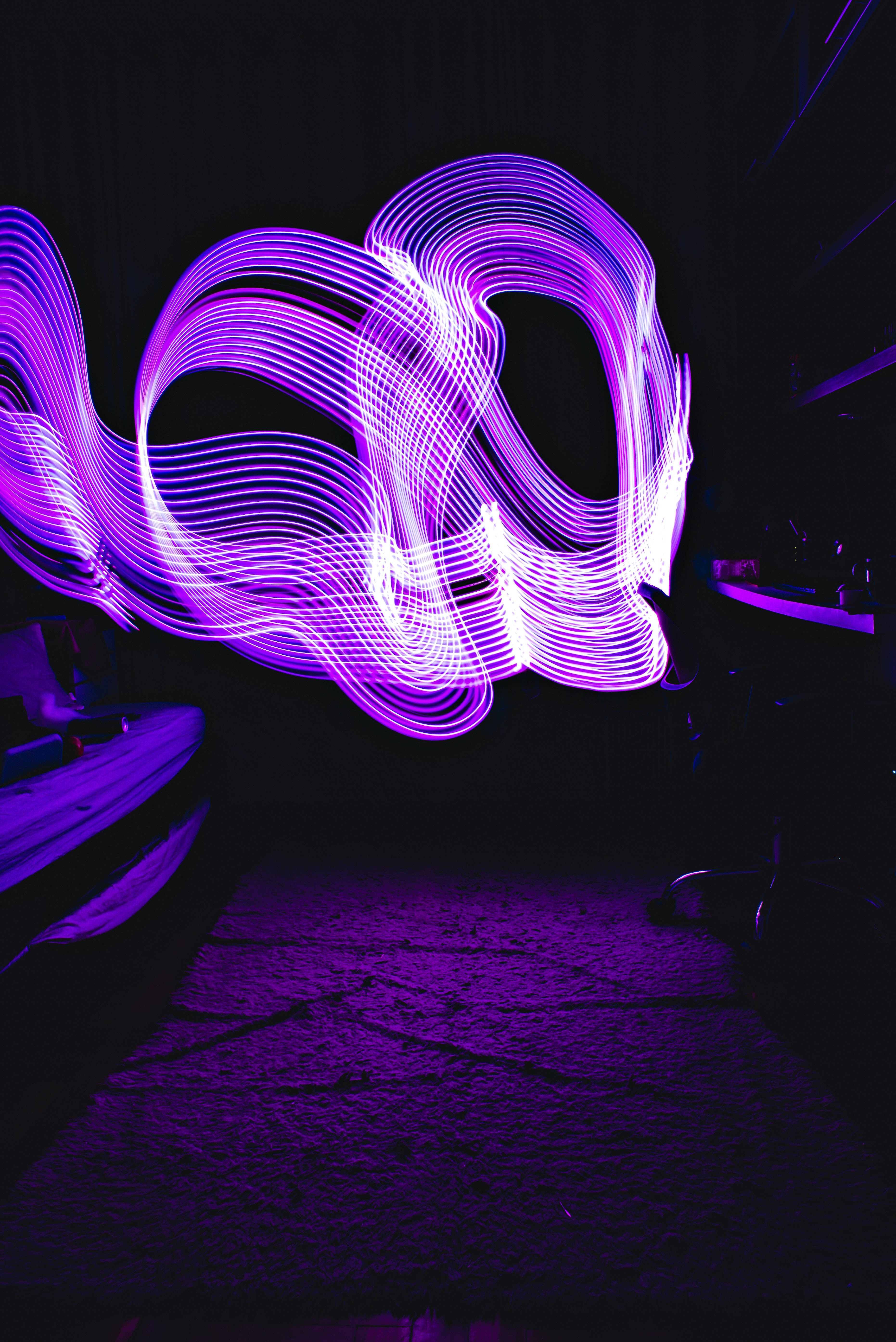 霓虹紫 iPhone 桌布 壁紙 — 鮮豔的紫色光軌在黑暗背景上動態旋轉，這是一張長曝光照片。