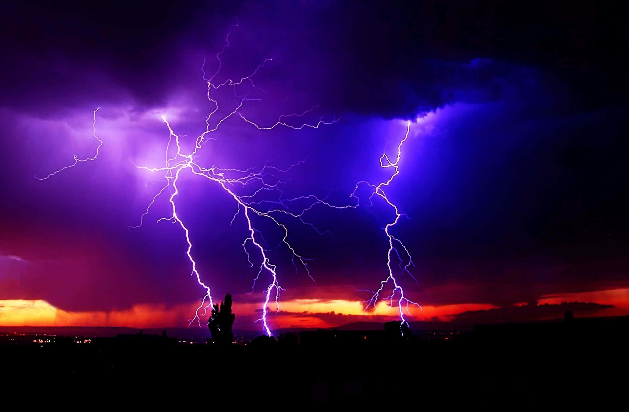 thunder 桌布 壁紙 — 鮮豔的紫色和橙色閃電照亮了黑暗剪影景觀上空的暴風雨夜空。