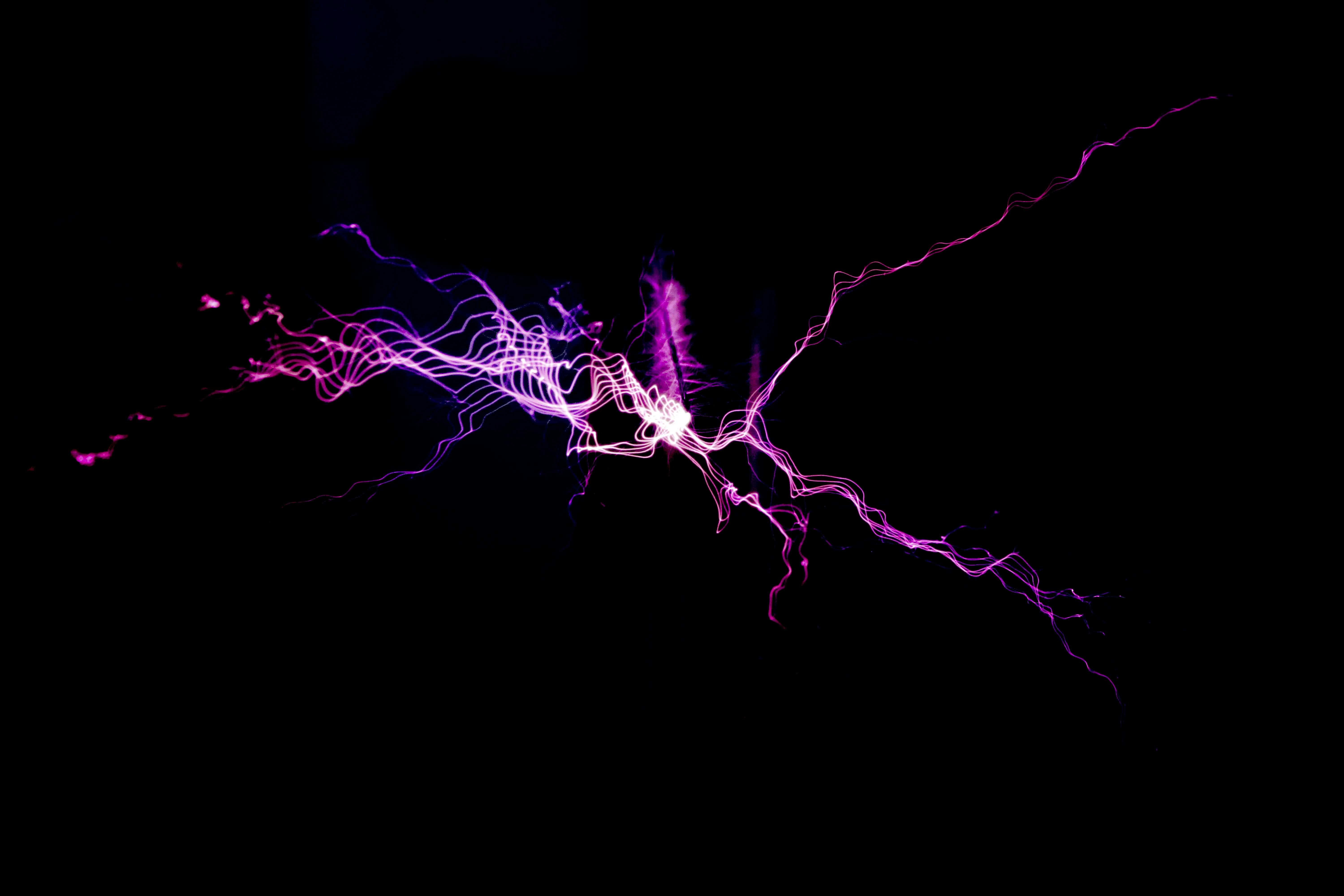 閃電 桌布 壁紙 — 鮮豔的紫色和白色電弧在漆黑的虛空中爆發，呈現動態的閃電顯示。