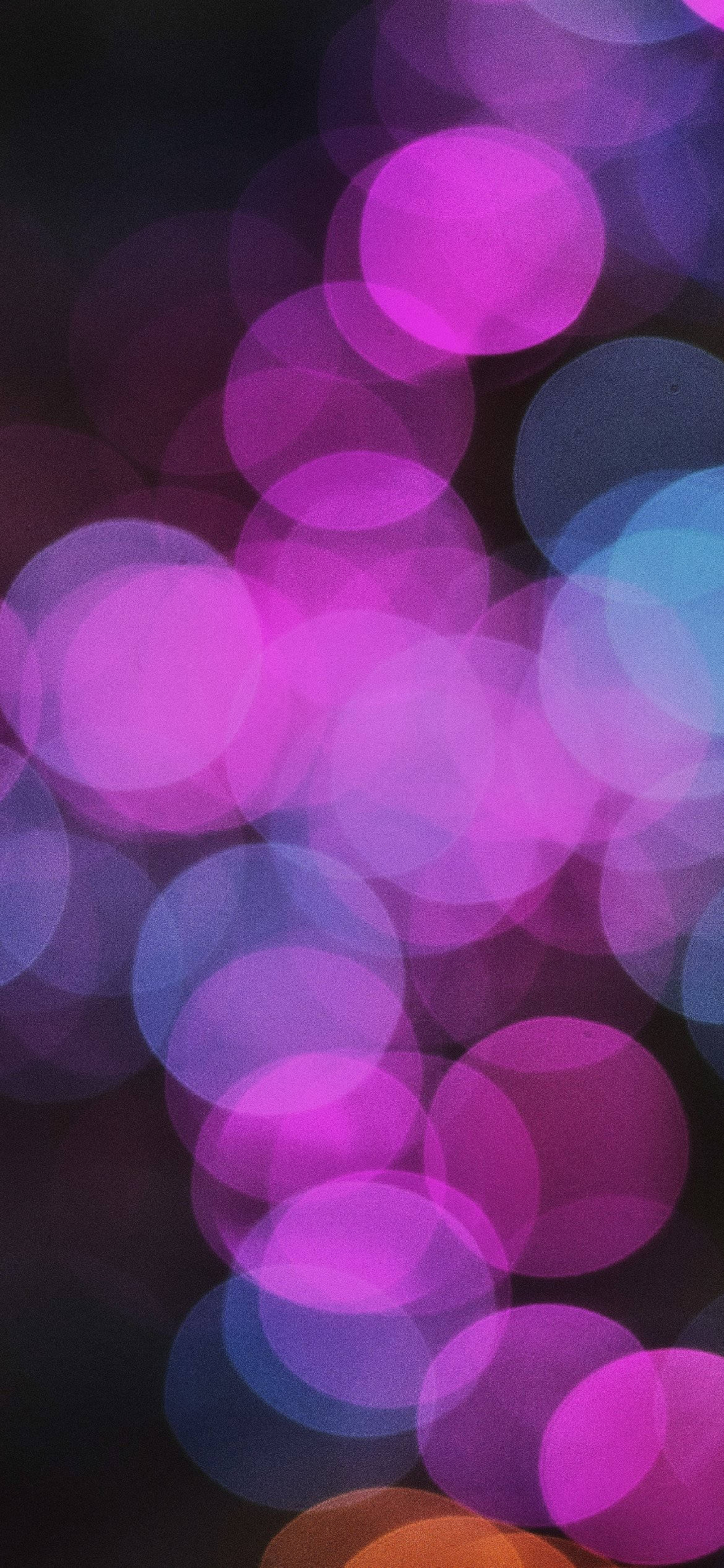 霓虹紫 iPhone 桌布 壁紙 — 鮮豔的紫色和藍色散景燈光在黑暗背景上柔和地發光，營造出夢幻般的抽象氛圍。