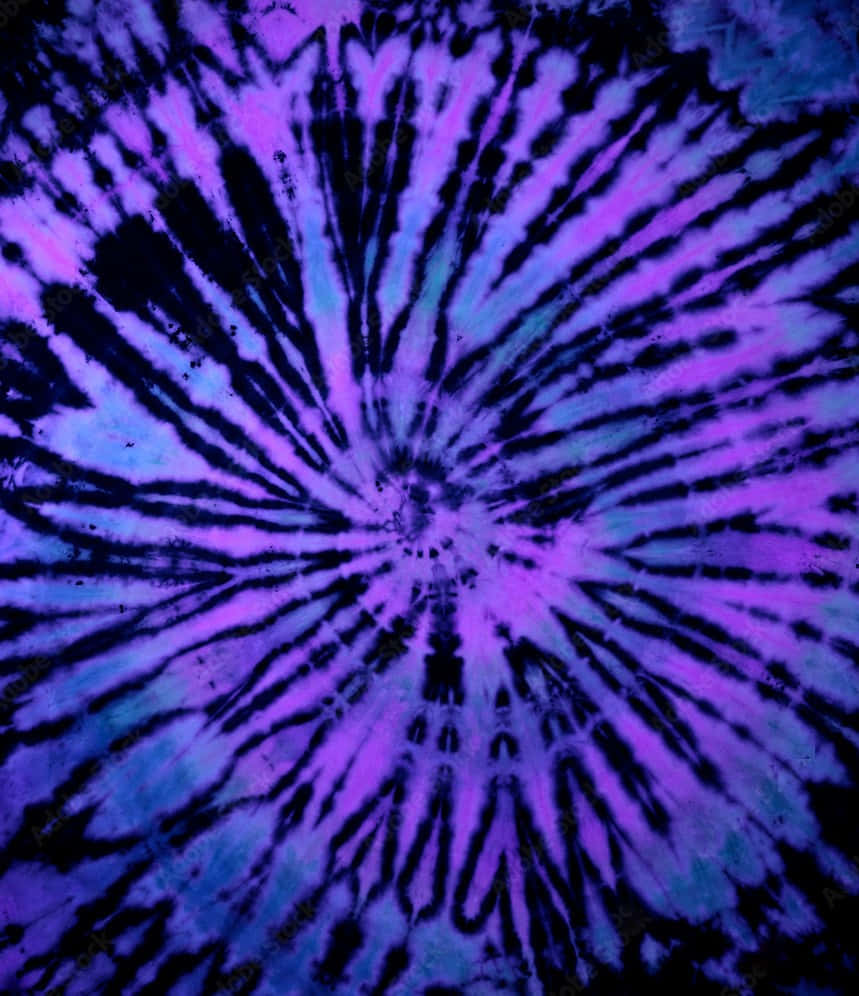 Purple Tie Dye 桌布 壁紙 — 鮮豔的紫色和藍色紮染在深色背景上以對稱螺旋圖案向外輻射。