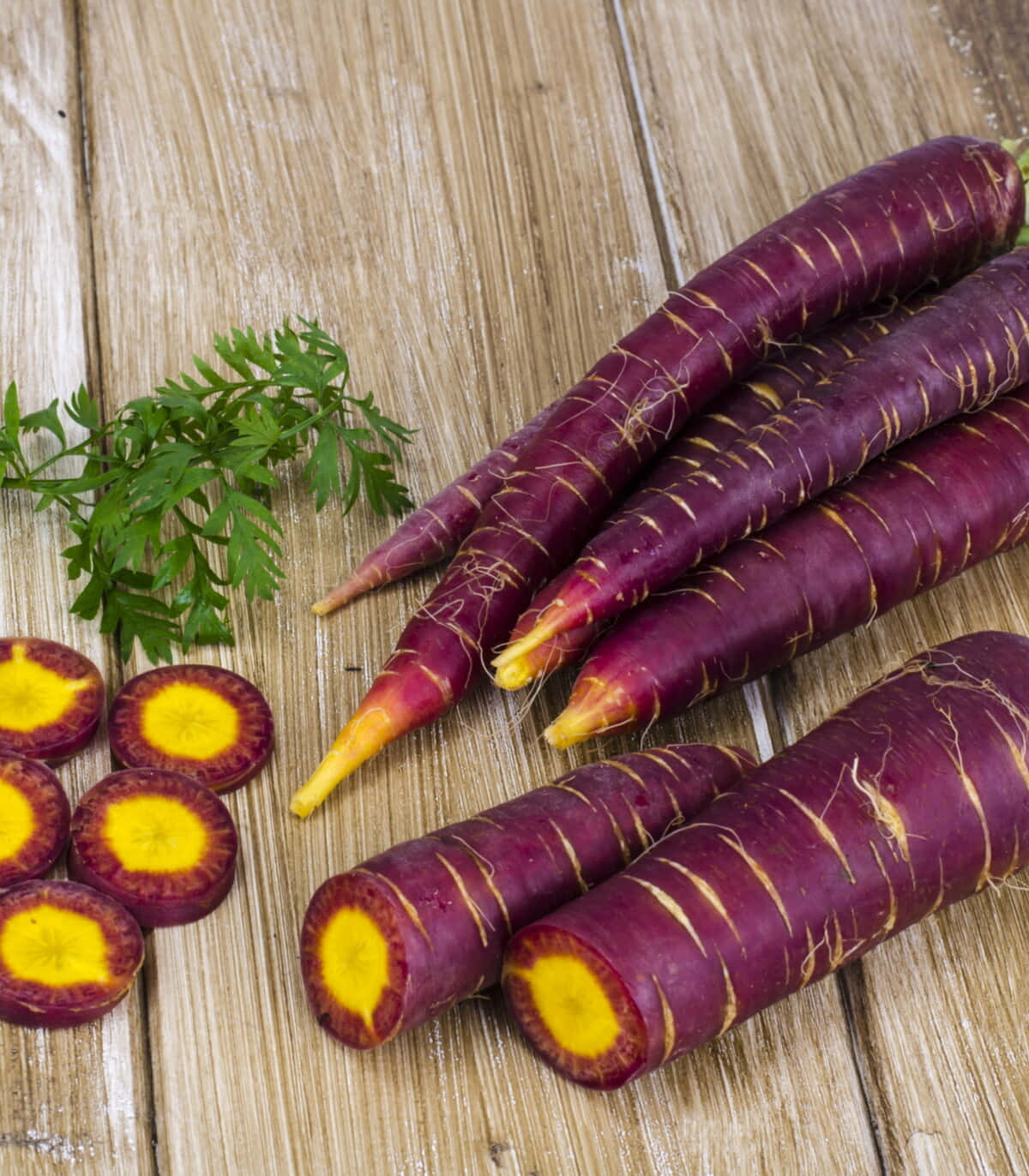 Purple Carrots 桌布 壁紙 — 鮮豔的紫色蘿蔔帶有金色內部，放在質樸的木板上，旁邊是新鮮的歐芹。