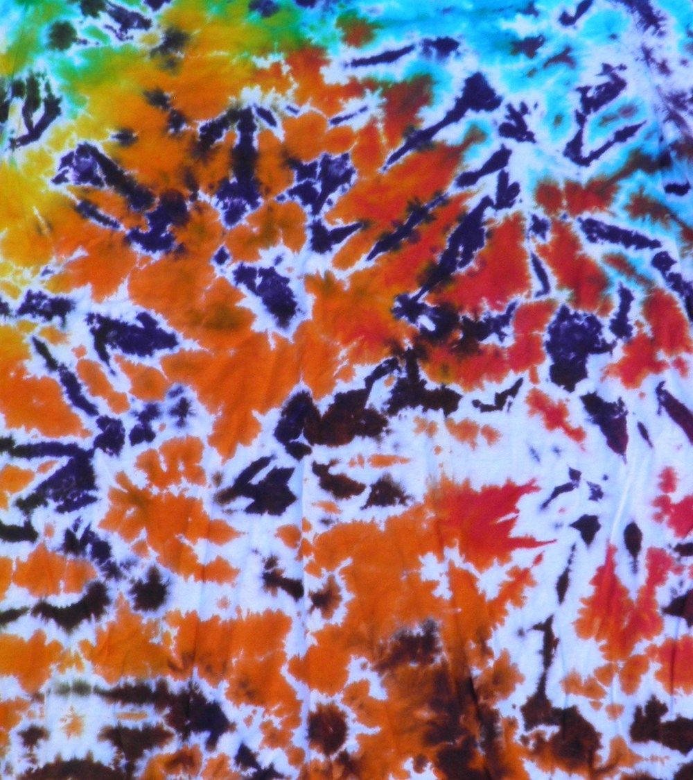 dye 桌布 壁紙 — 鮮豔的紮染布料在白色背景上呈現火熱的橙色、紅色、紫色和藍綠色漩渦。