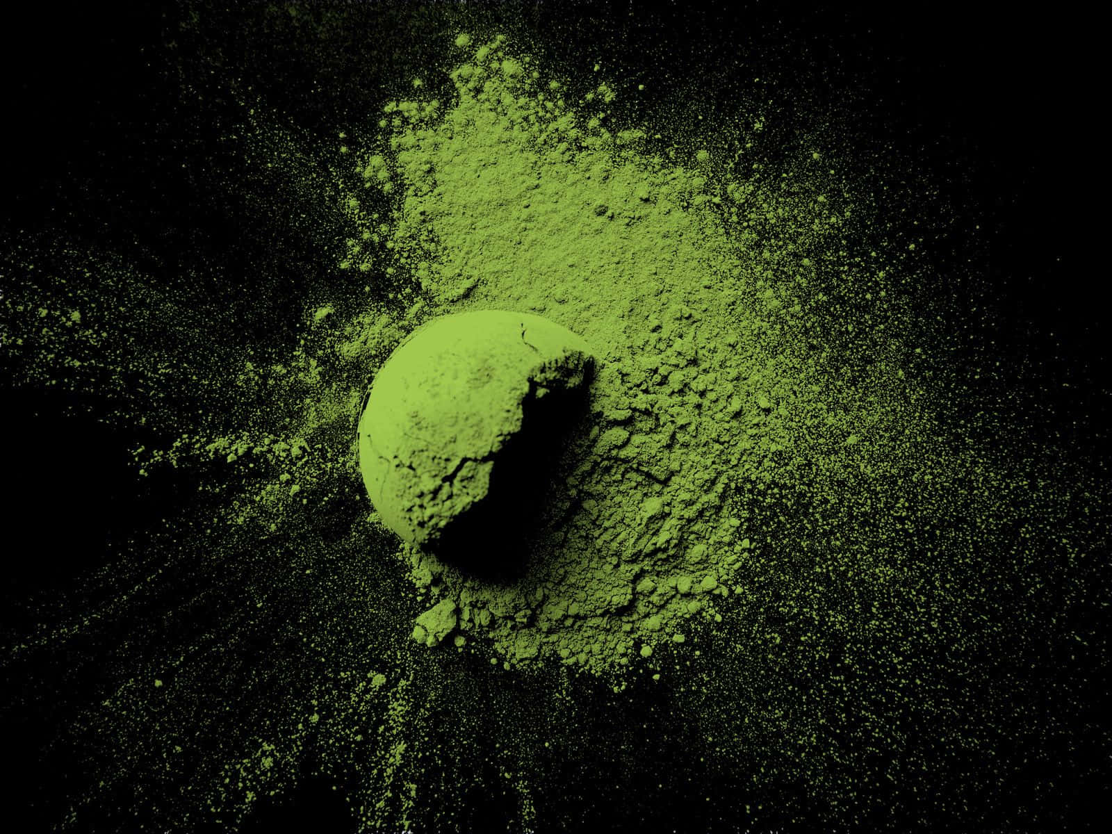 Matcha 桌布 壁紙 — 鮮豔的綠色粉末爆炸從中央球體向純黑背景輻射開來。