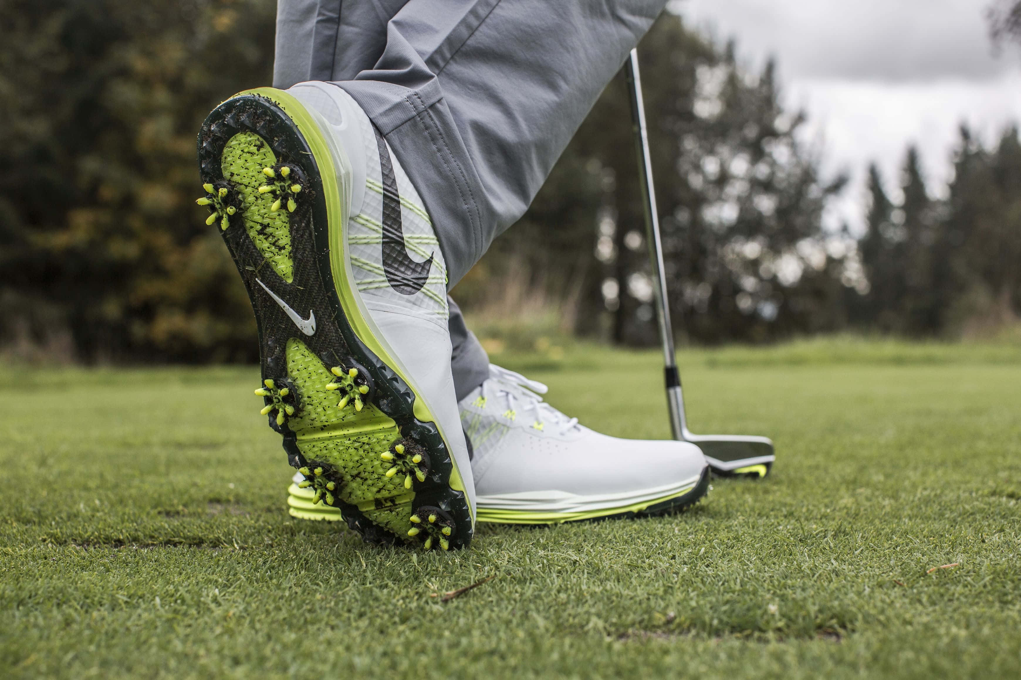 Golf Club 桌布 壁紙 — 鮮豔的萊姆綠色和白色高爾夫球鞋特寫，黑色鞋釘，在茂盛的綠色球道旁的高爾夫球桿。
