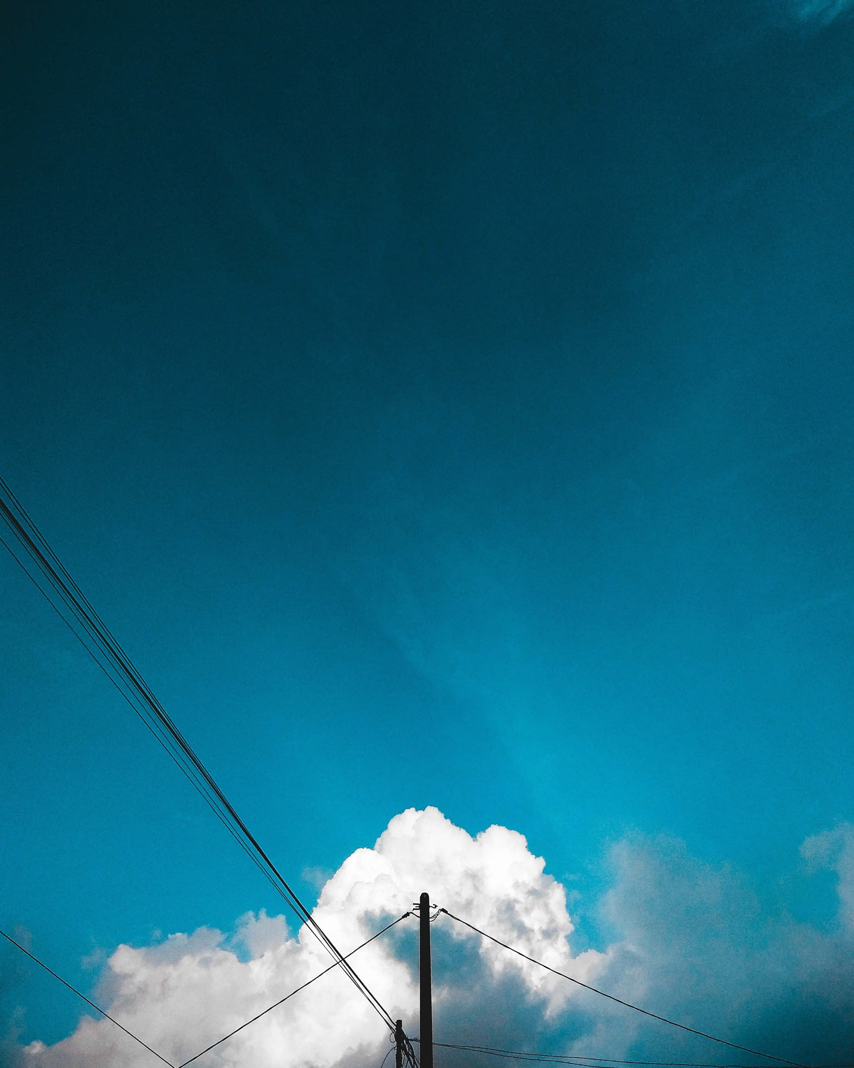 Minimalist Sky 桌布 壁紙 — 鮮豔的藍天與蓬鬆的白雲，由深色電線和電線桿框起。