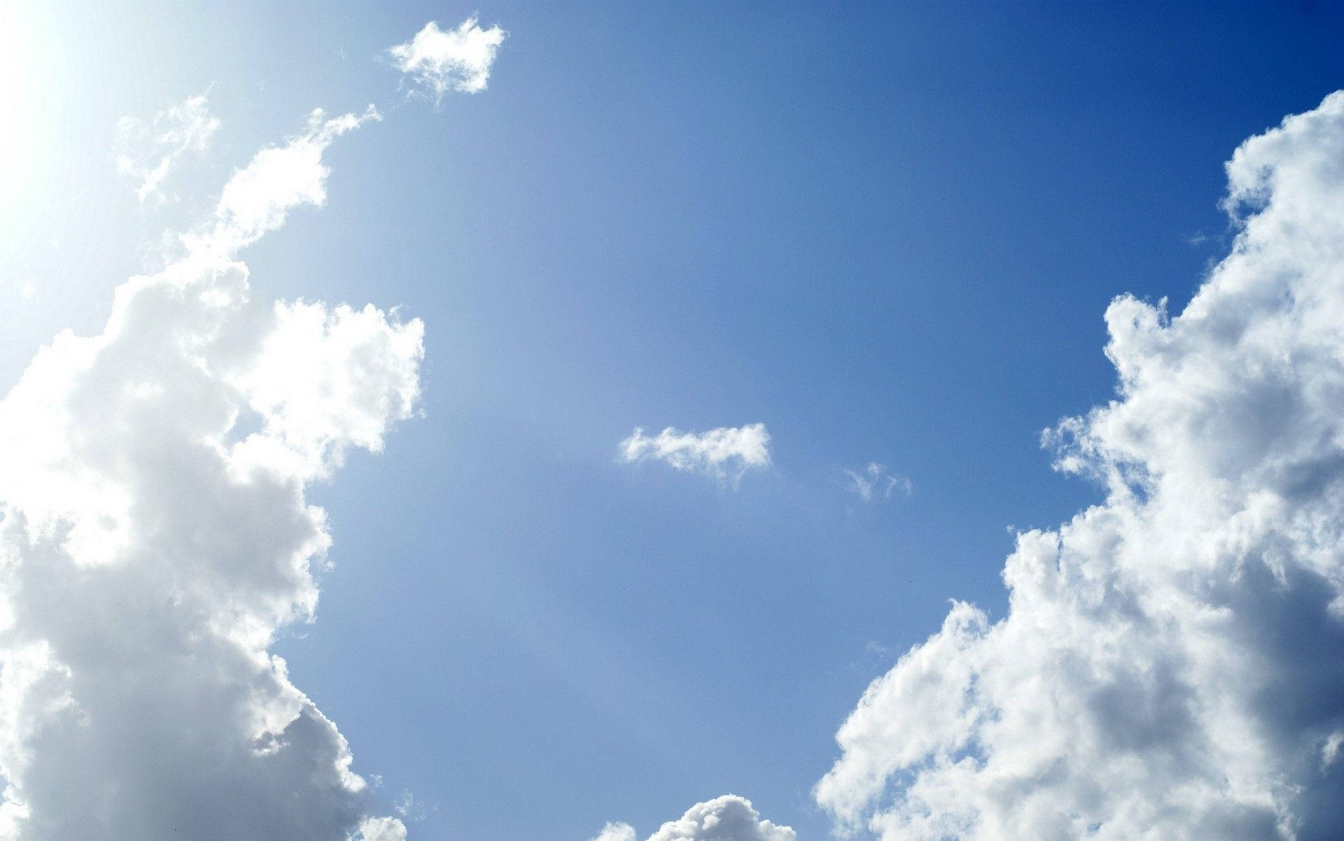 天空 桌布 壁紙 — 鮮豔的藍天被蓬鬆的白雲框住，明亮的陽光穿透而過。