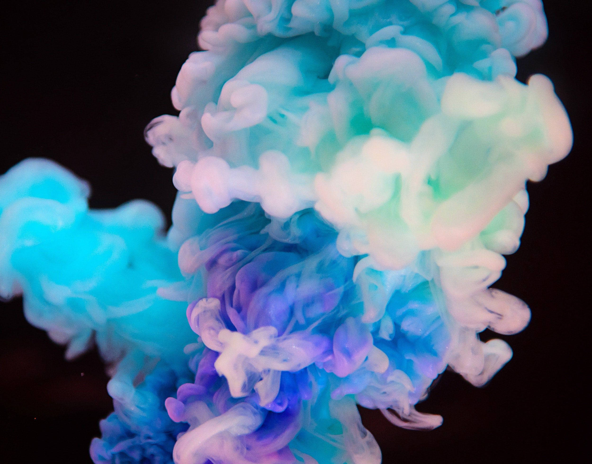 Blue Smoke 桌布 壁紙 — 鮮豔的藍色和紫色墨水在黑色背景的水中旋轉，營造出夢幻般的抽象動感。