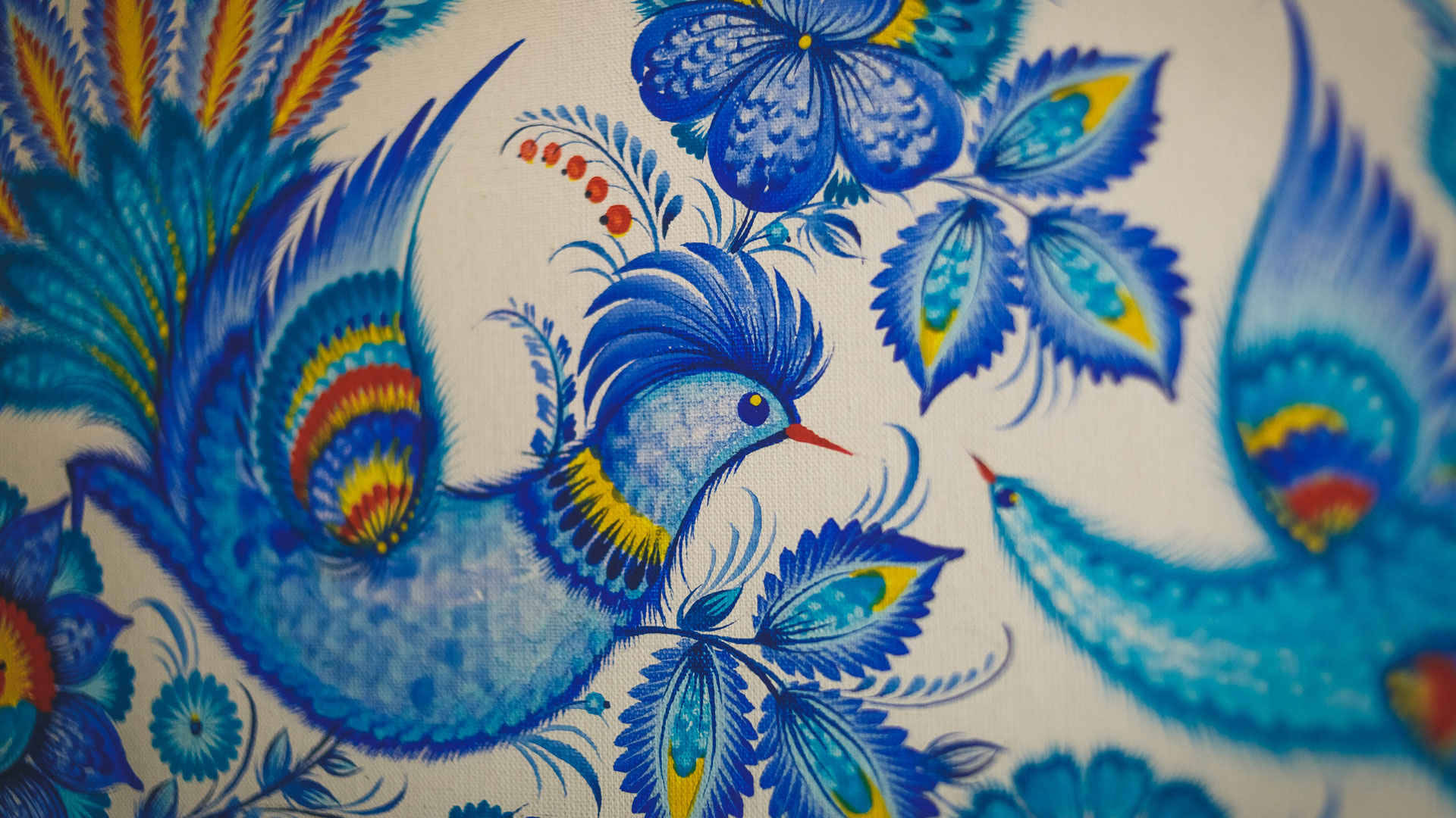 Folk Art 桌布 壁紙 — 鮮豔的藍色和黃色風格化鳥類和花朵，在紋理布料上呈現複雜的民間藝術圖案。