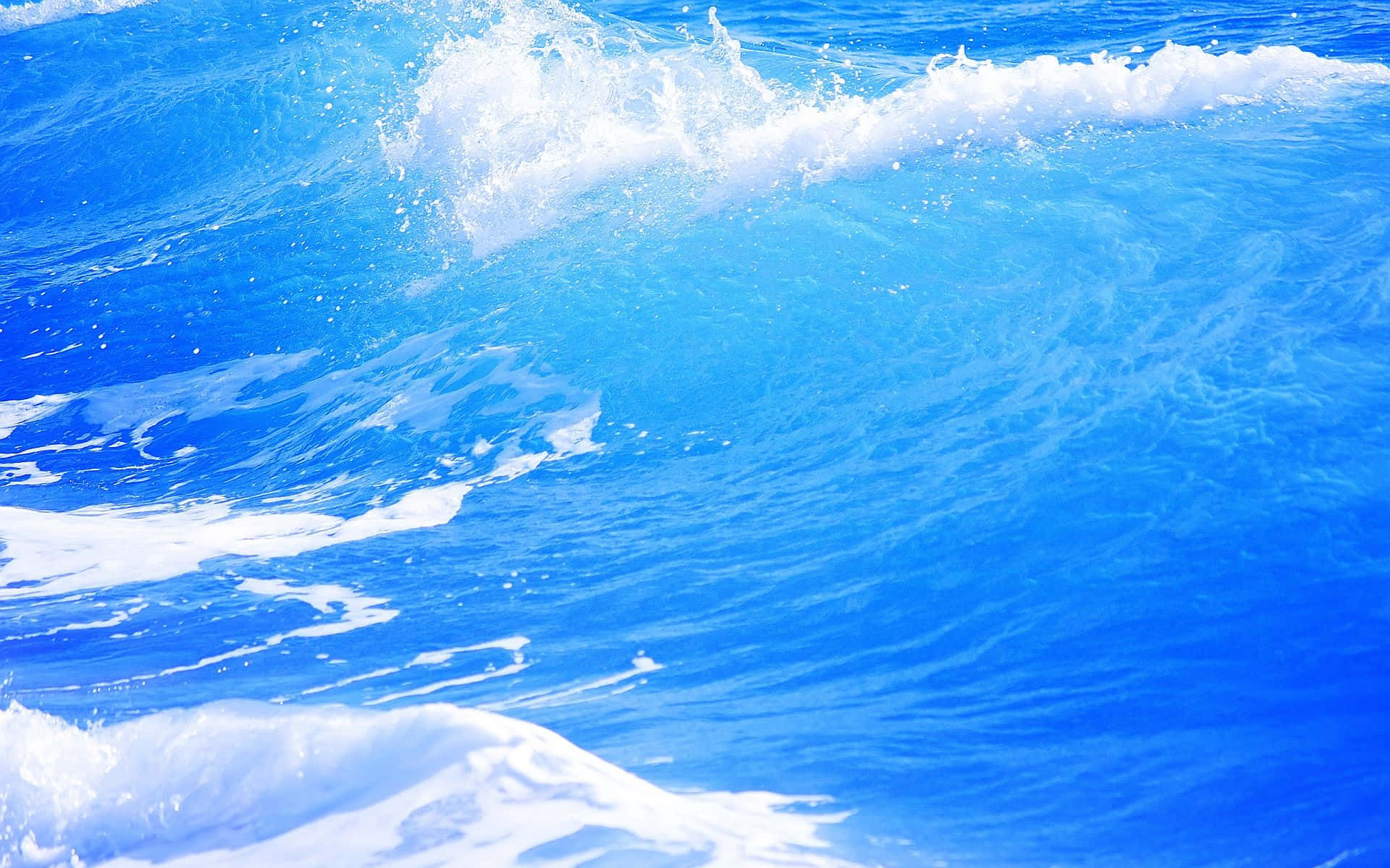 Ocean Waves 桌布 壁紙 — 鮮豔的藍色海浪在明亮的陽光下撞擊出白色泡沫，營造出動態的運動感。