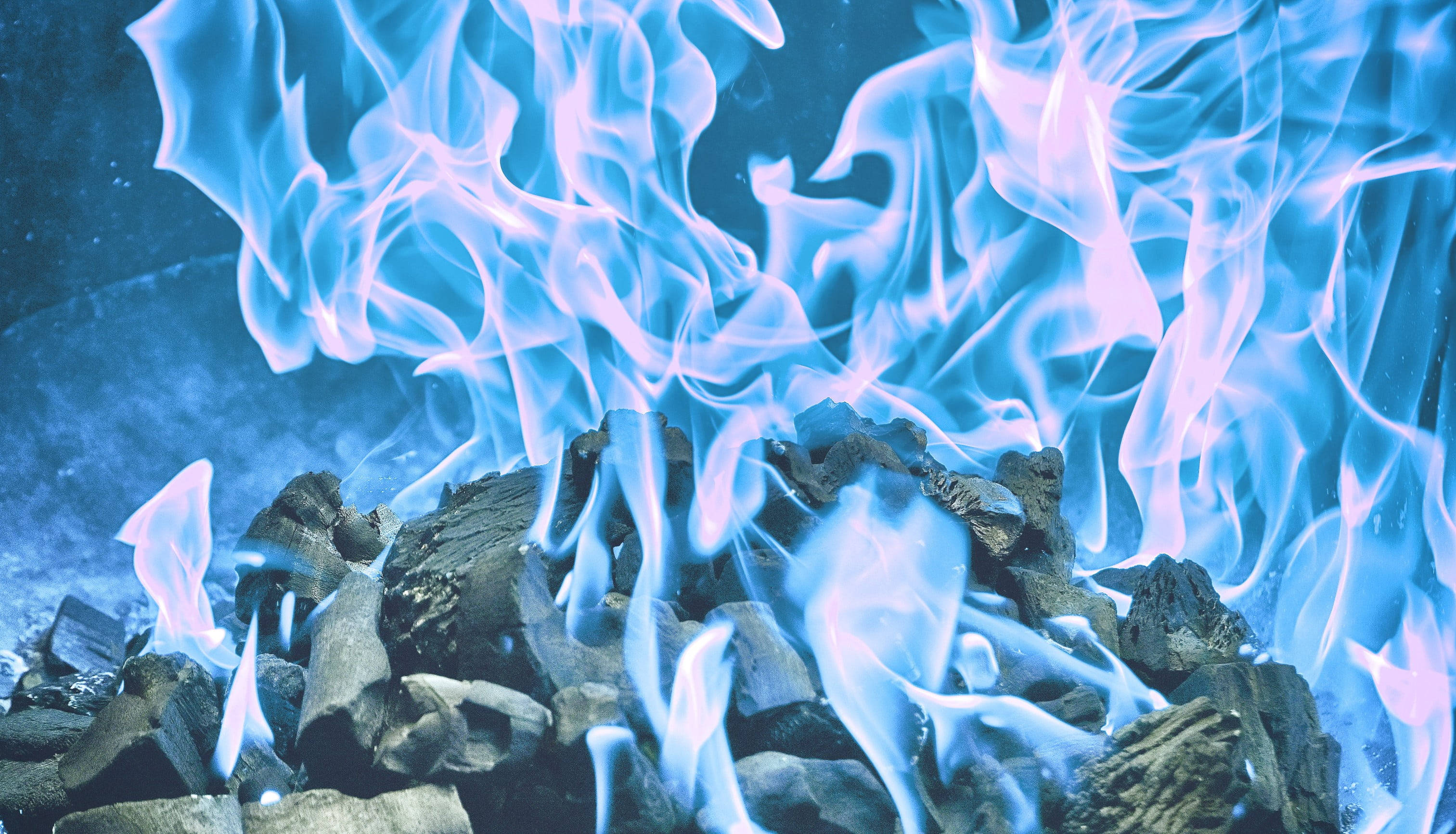 Flame 桌布 壁紙 — 鮮豔的藍色火焰在深色燒焦的木炭上優雅舞動，呈現冷色調特寫。