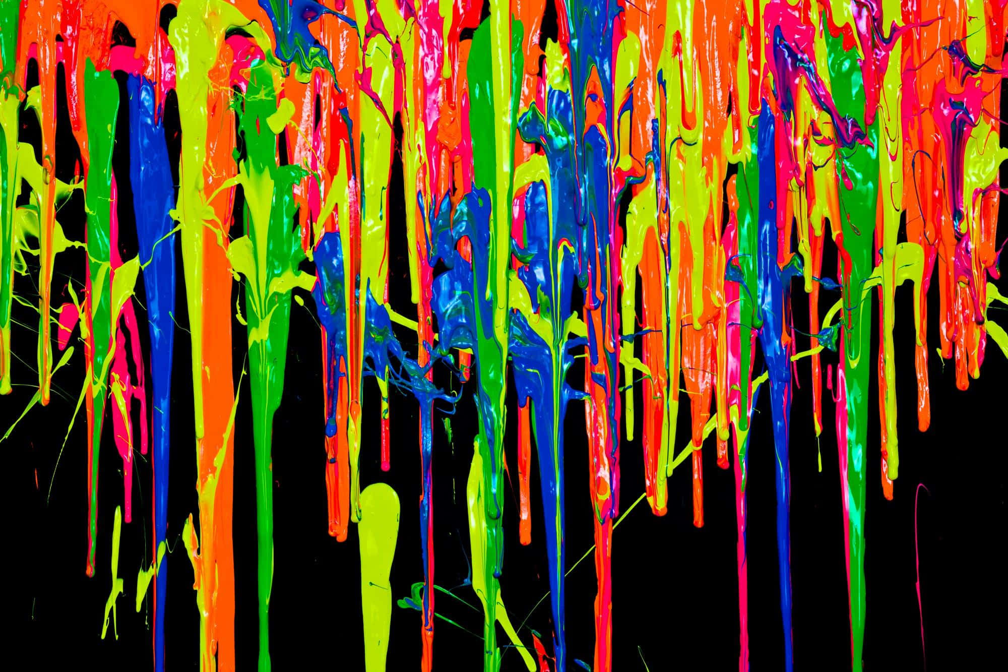 paint 桌布 壁紙 — 鮮豔的螢光顏料滴在黑色表面上如瀑布般流下，形成混亂的色彩爆炸。