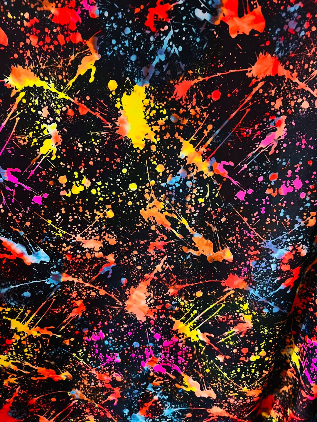 藝術 桌布 壁紙 — 鮮豔的螢光顏料飛濺在深黑色布料上爆炸開來，形成混亂而充滿活力的抽象圖案。