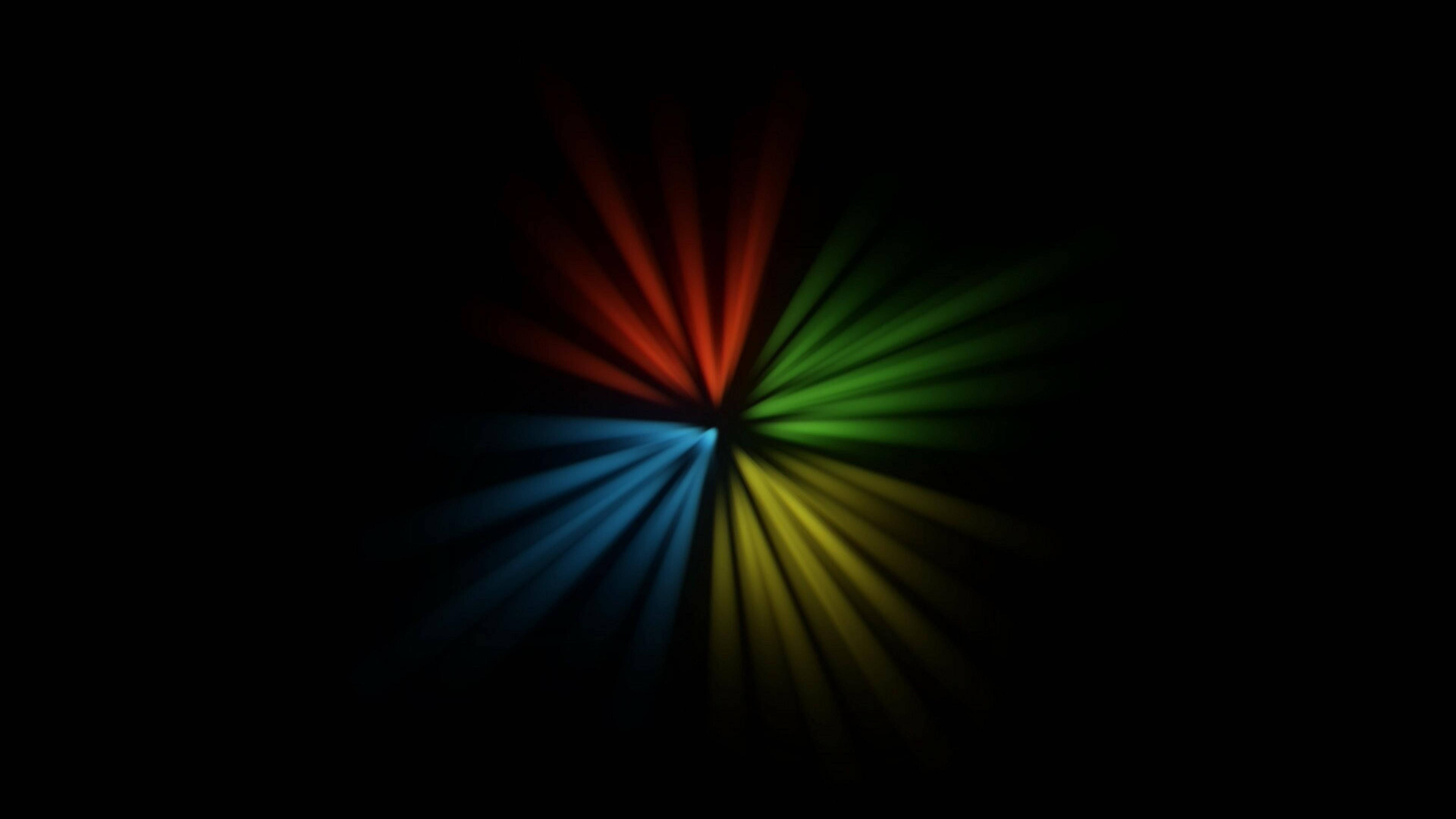 AMOLED 4K 桌布 壁紙 — 鮮豔的雷射光束從中心點向外輻射，在漆黑的背景上呈現紅、綠、藍、黃的光譜。