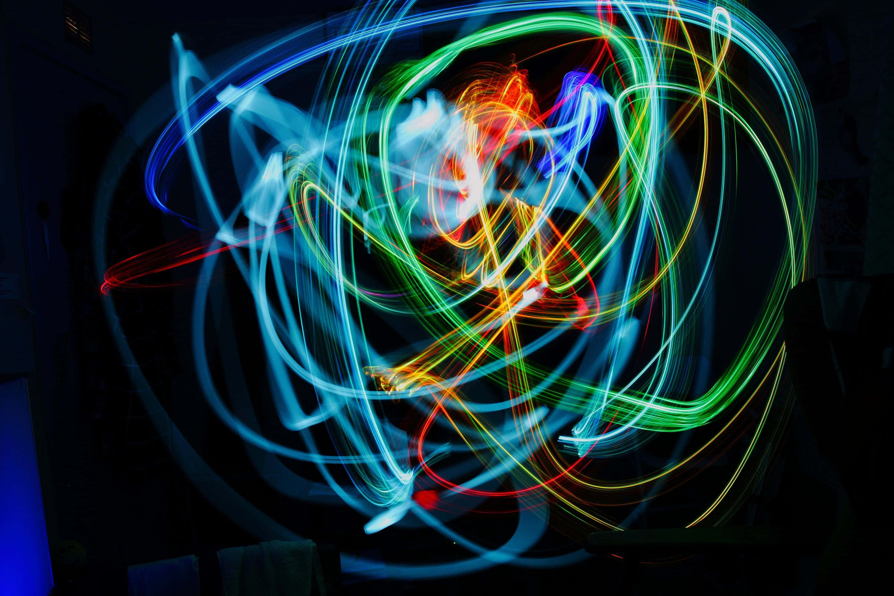 Trippy Neon Lights 桌布 壁紙 — 鮮豔的霓虹光軌在漆黑背景上以混亂的美感旋轉，創造出電動抽象舞蹈。