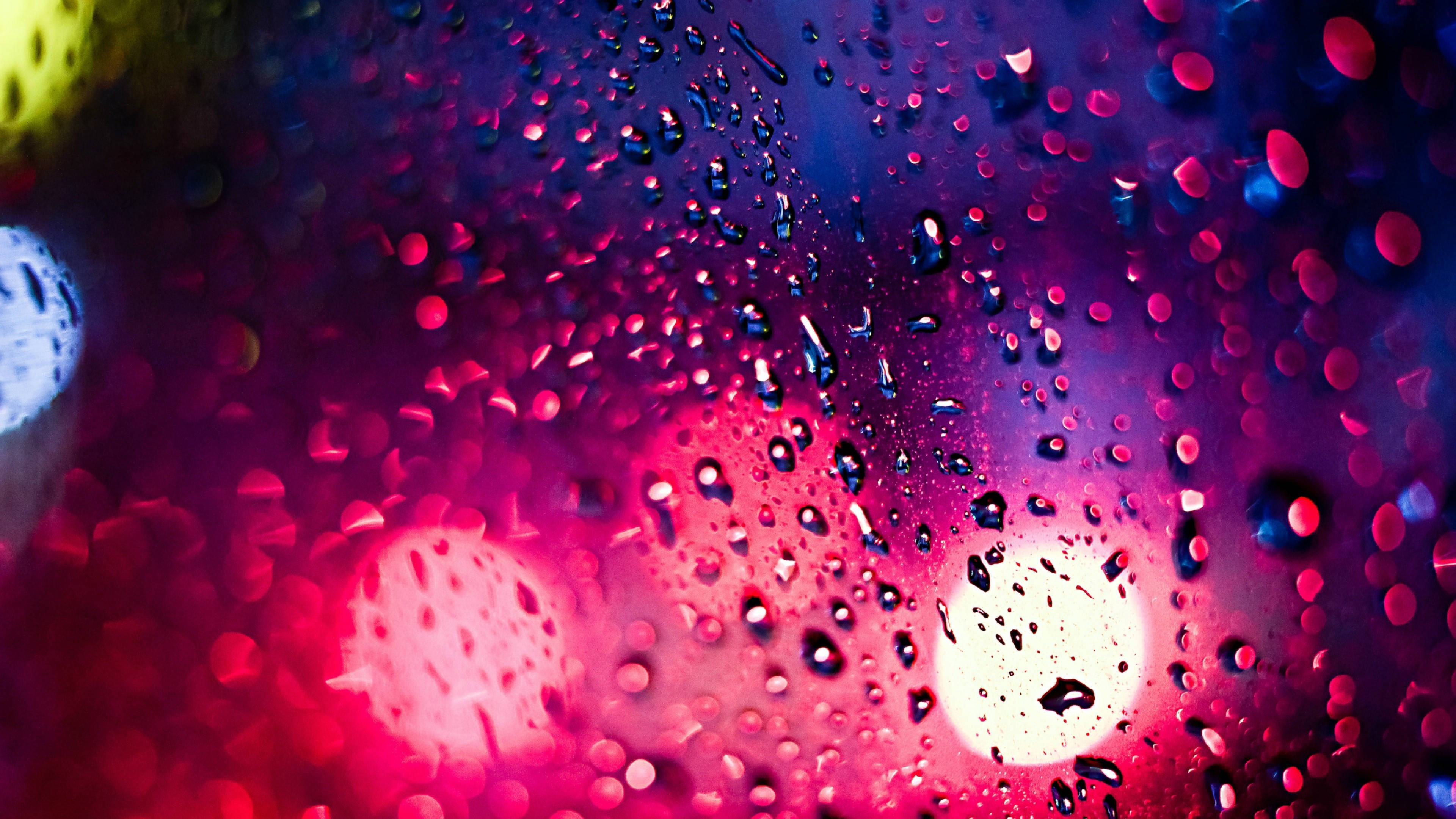Rainy Day 桌布 壁紙 — 鮮豔的霓虹燈光透過雨水濕潤的玻璃模糊，營造出夢幻般的城市夜景，帶有發光散景和閃爍的水滴。