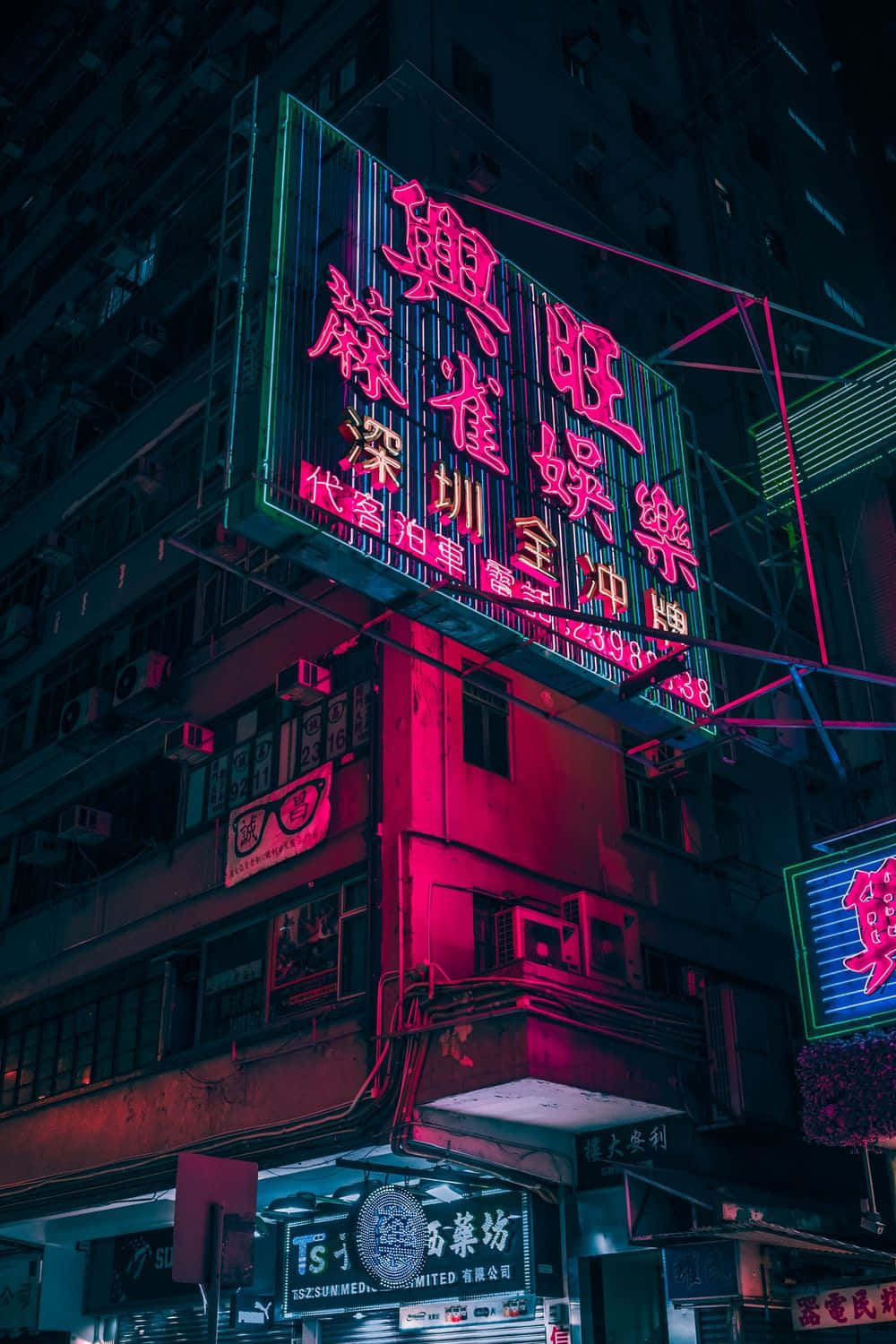 電馭叛客2077 桌布 壁紙 — 鮮豔的霓虹燈在夜晚的黑暗城市建築外牆上發出粉紅色和綠色的光芒。