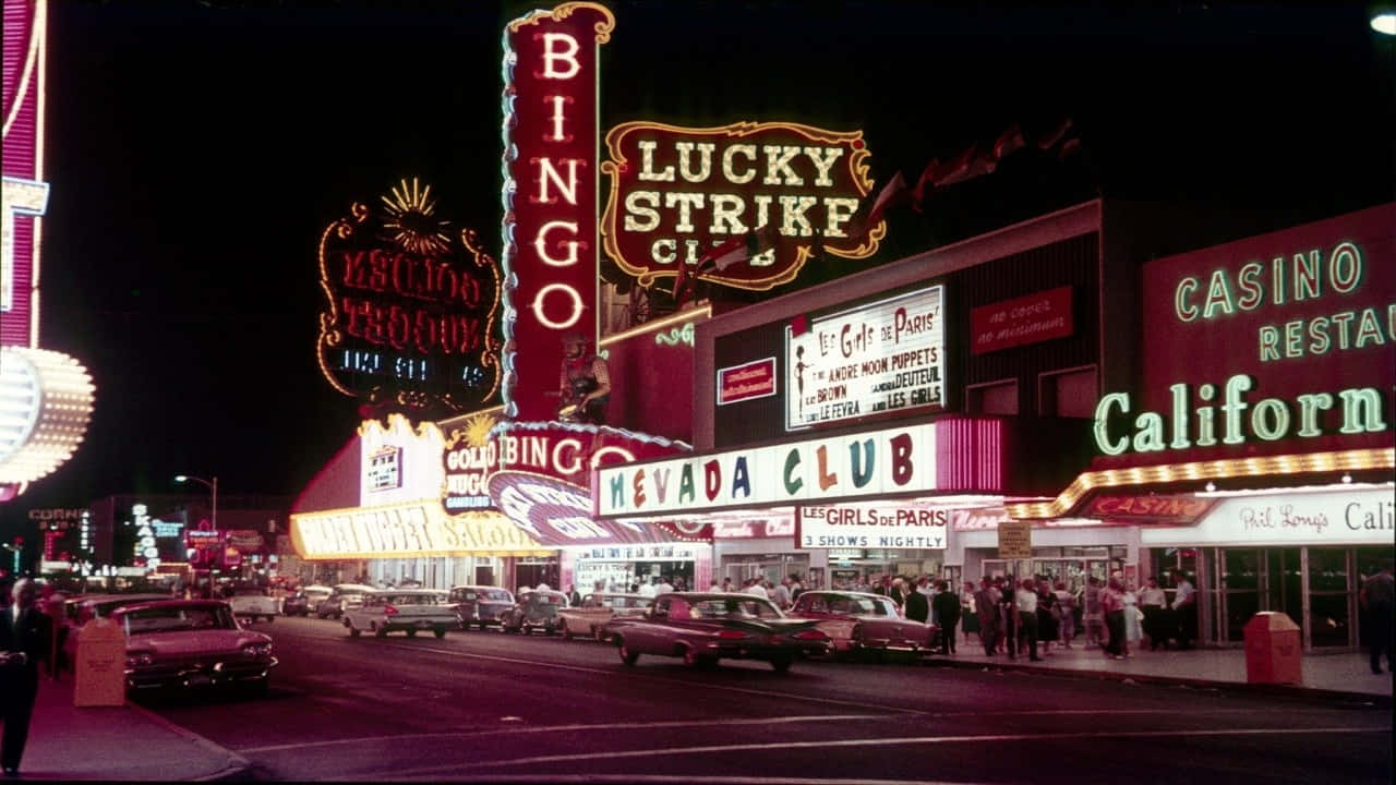 720p Las Vegas 桌布 壁紙 — 鮮豔的霓虹燈照亮了1950年代熱鬧的拉斯維加斯大道夜景，配有復古汽車和人群。
