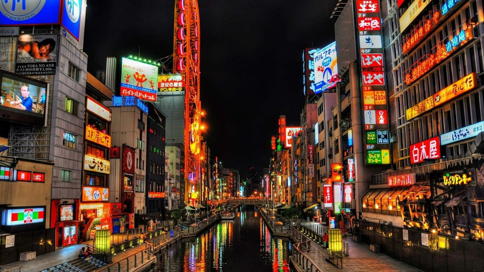 城市 桌布 壁紙 — 鮮豔的霓虹燈照亮了夜晚繁忙的東京運河，在黑暗的水面上反射出五彩繽紛的光芒。