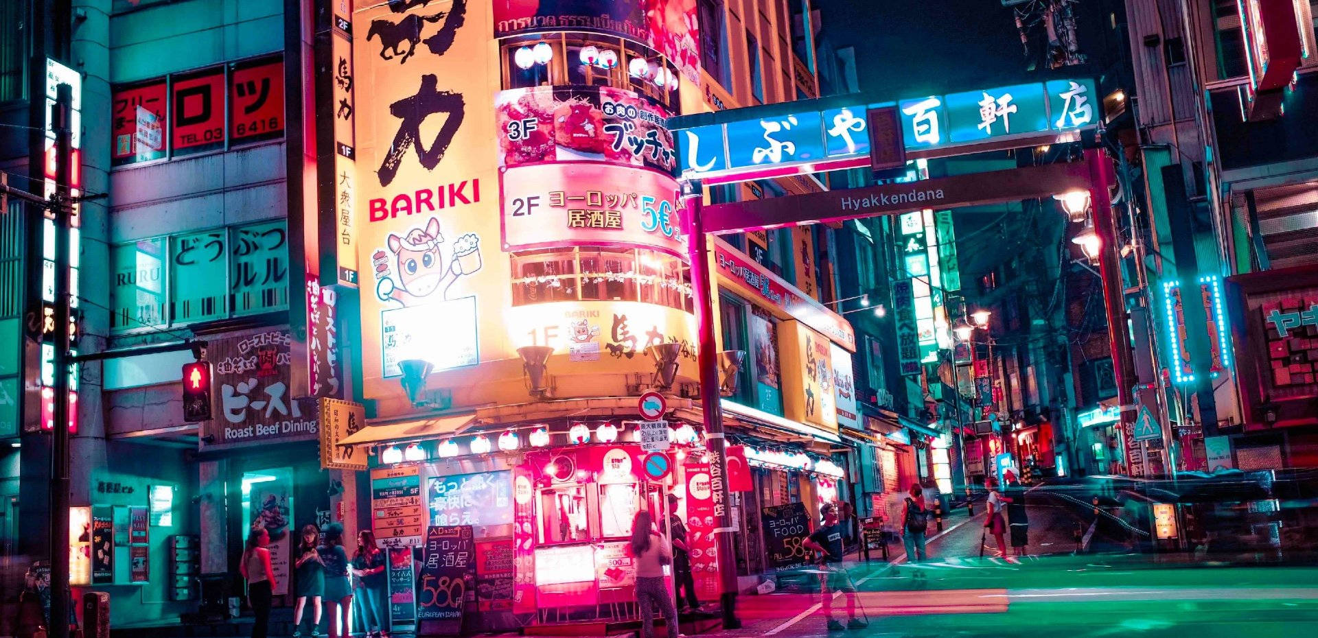 日本 桌布 壁紙 — 鮮豔的霓虹燈照亮了夜晚繁華的東京街道，粉紅色、藍色和黃色的燈光在潮濕的人行道上反射。