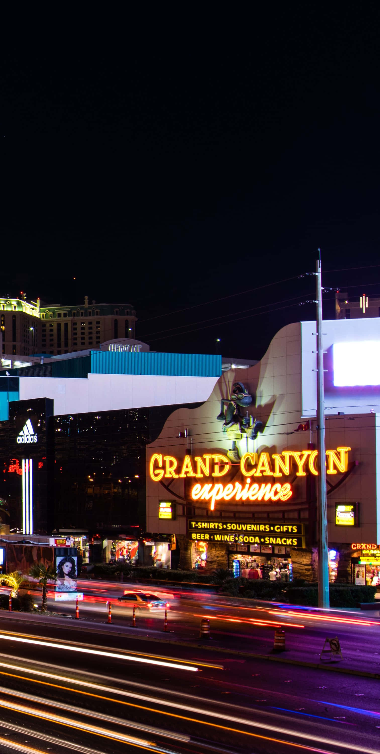 Las Vegas Phone 桌布 壁紙 — 鮮豔的霓虹燈照亮了繁華的拉斯維加斯夜晚，下方有汽車燈光形成的流線。