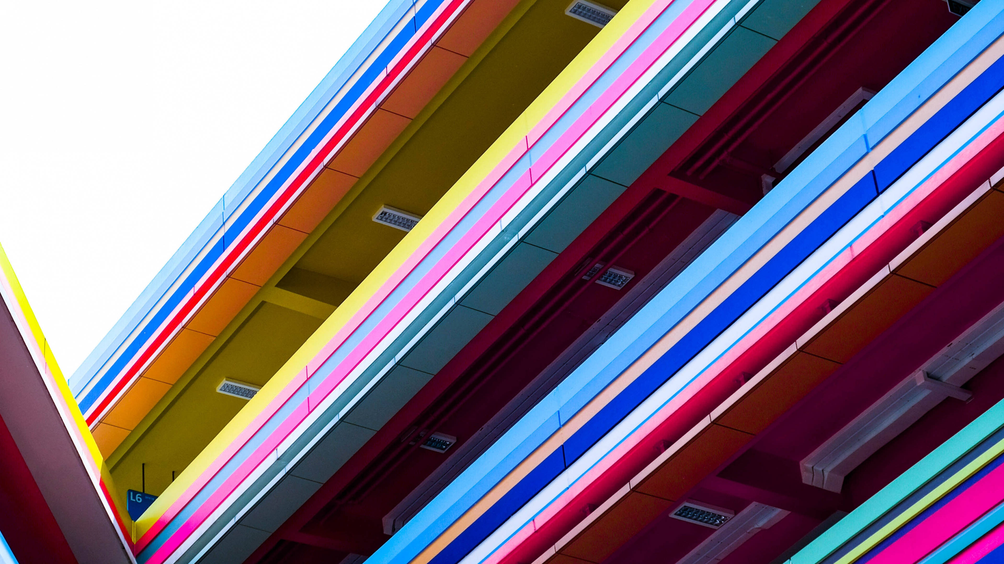 Building 桌布 壁紙 — 鮮豔的霓虹色對角條紋在明亮的日光下，如瀑布般流過現代建築的外牆。