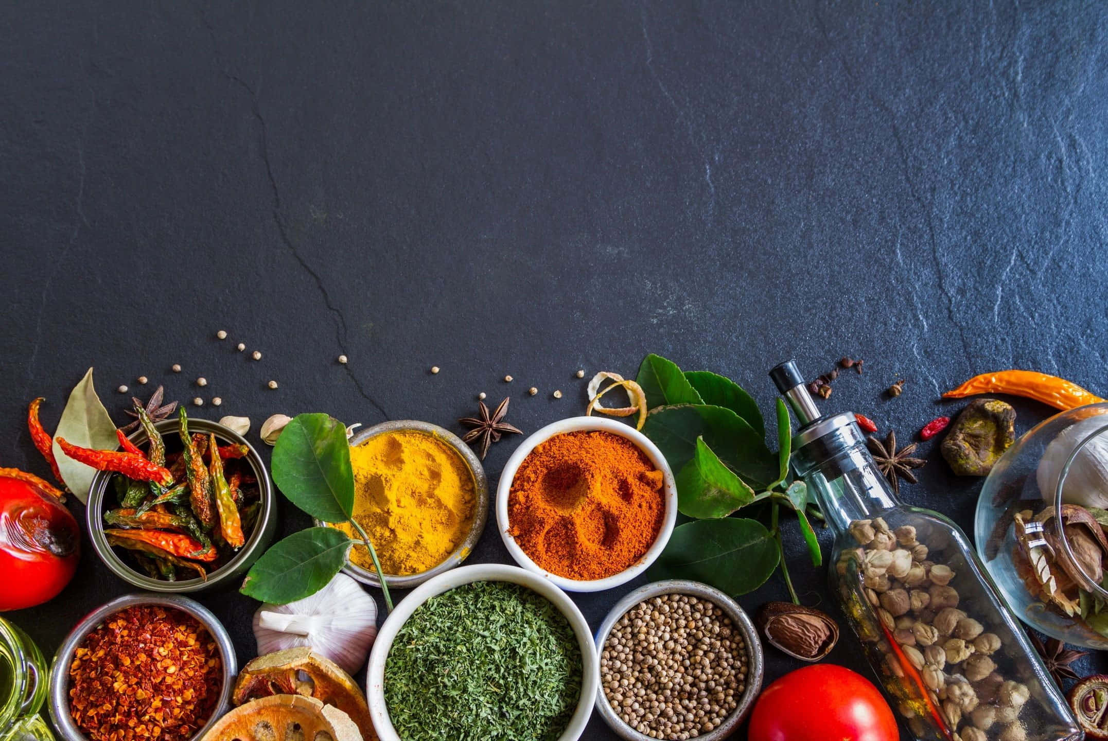 Indian 桌布 壁紙 — 鮮豔的香料和香草放在碗和罐子裡，排列在深色石板表面上。