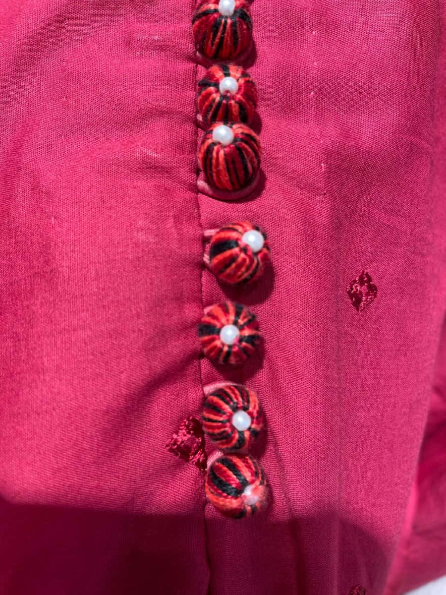 Buttons 桌布 壁紙 — 鮮豔粉紅色布料的特寫，帶有醒目的紅黑條紋鈕扣，每顆鈕扣頂部飾有一顆珍珠。