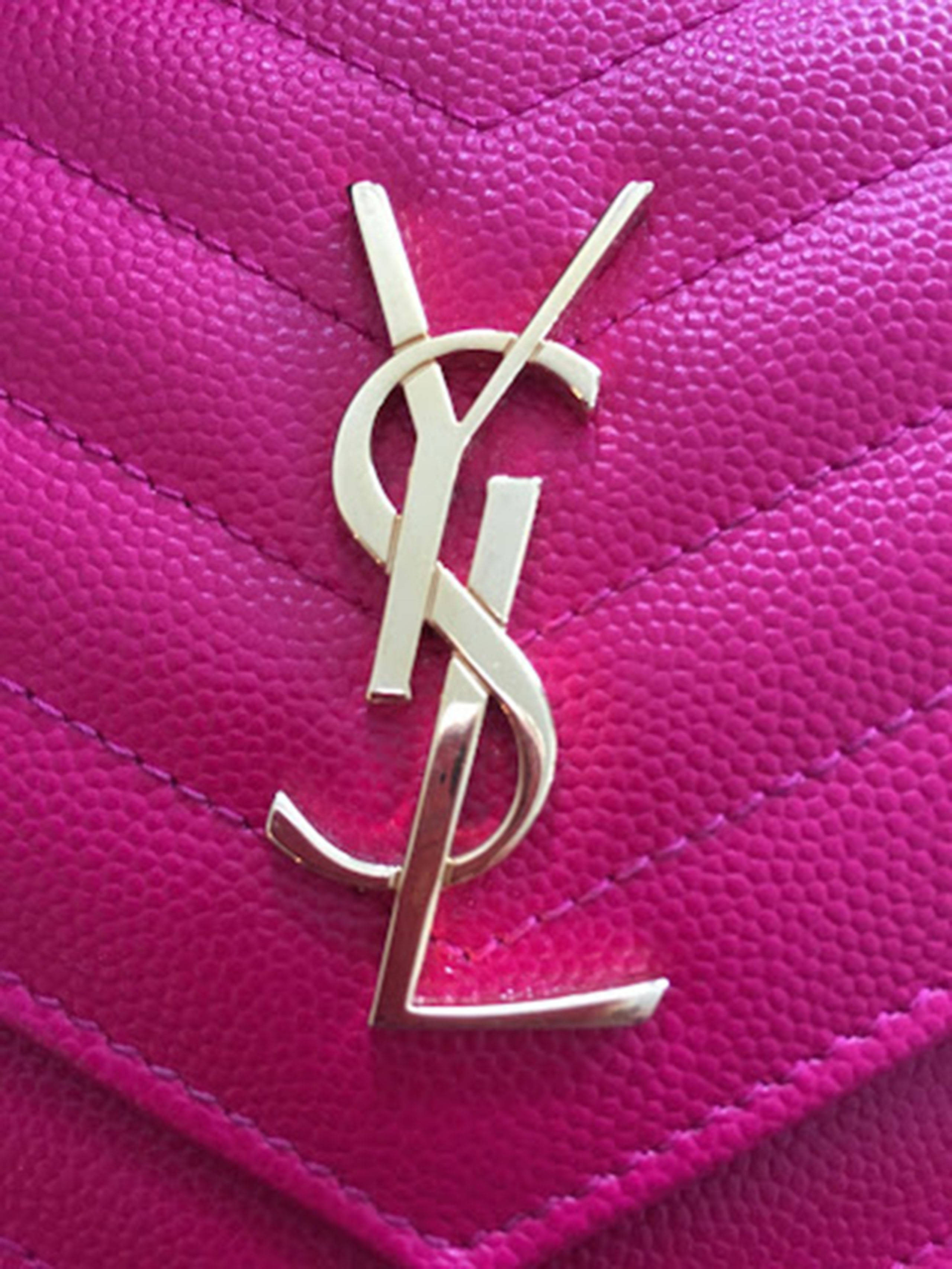 Ysl 桌布 壁紙 — 鮮豔粉紅色絎縫皮革手袋的特寫，飾有閃亮的金色YSL字母組合標誌。