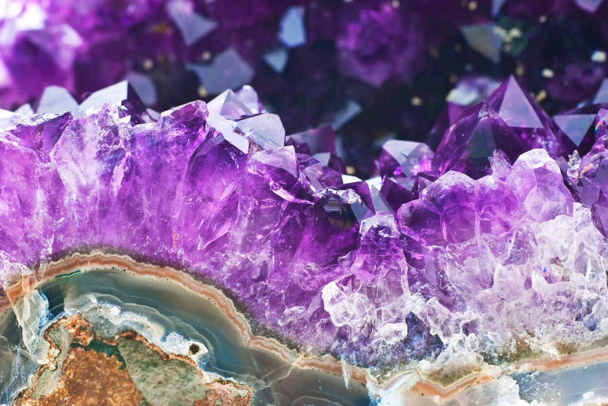 紫水晶 桌布 壁紙 — 鮮豔紫色紫水晶晶體密集簇生，帶有銳利刻面及半透明光澤，生長於層狀瑪瑙基底上。