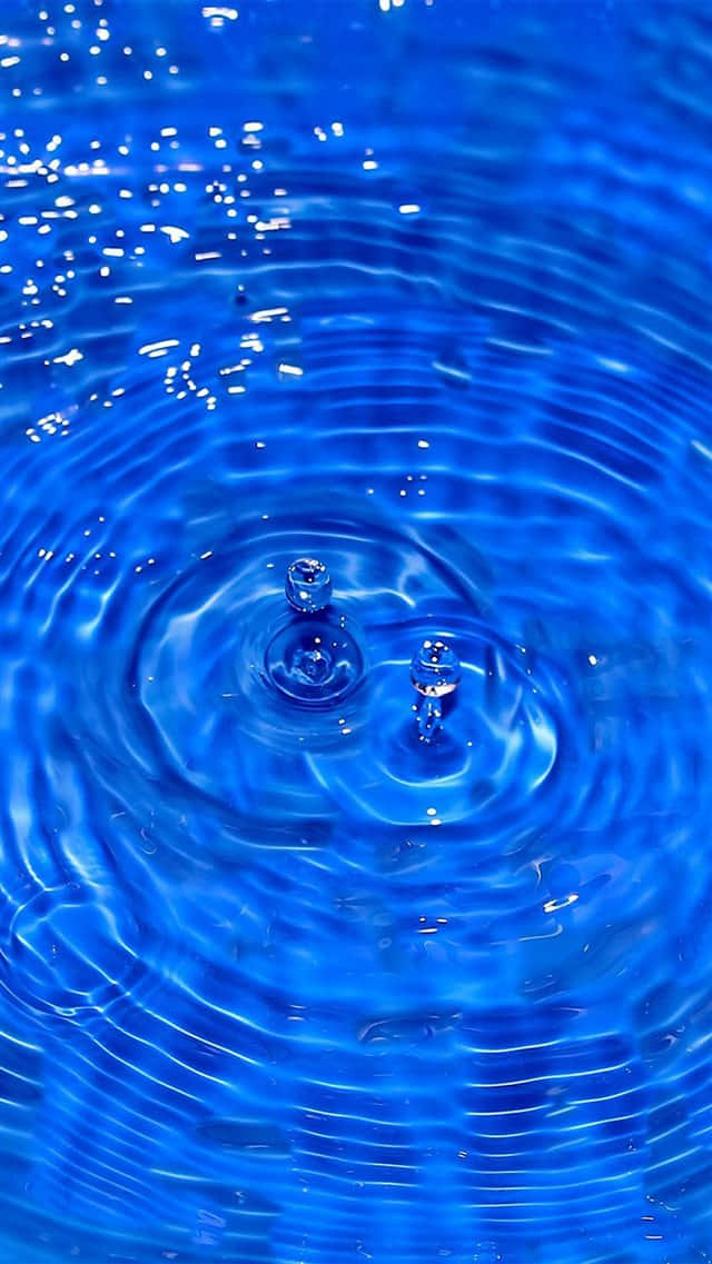 Blue iPhone Xr 桌布 壁紙 — 鮮豔藍色水面的特寫，兩個水滴產生同心漣漪擴散，形成完美的球形氣泡。
