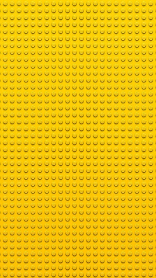 540x960 桌布 壁紙 — 鮮黃色LEGO底板的特寫，表面覆蓋均勻的圓形凸點。