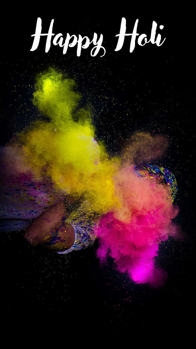 Holi 桌布 壁紙 — 鮮黃色和粉紅色的粉末在黑色背景上爆炸，上方有「Happy Holi」文字。