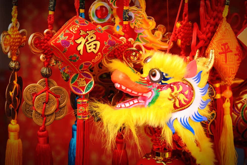 春節 桌布 壁紙 — 鮮黃色的中國舞龍頭，周圍環繞著紅色節日裝飾品和金幣，背景是濃郁的紅色。
