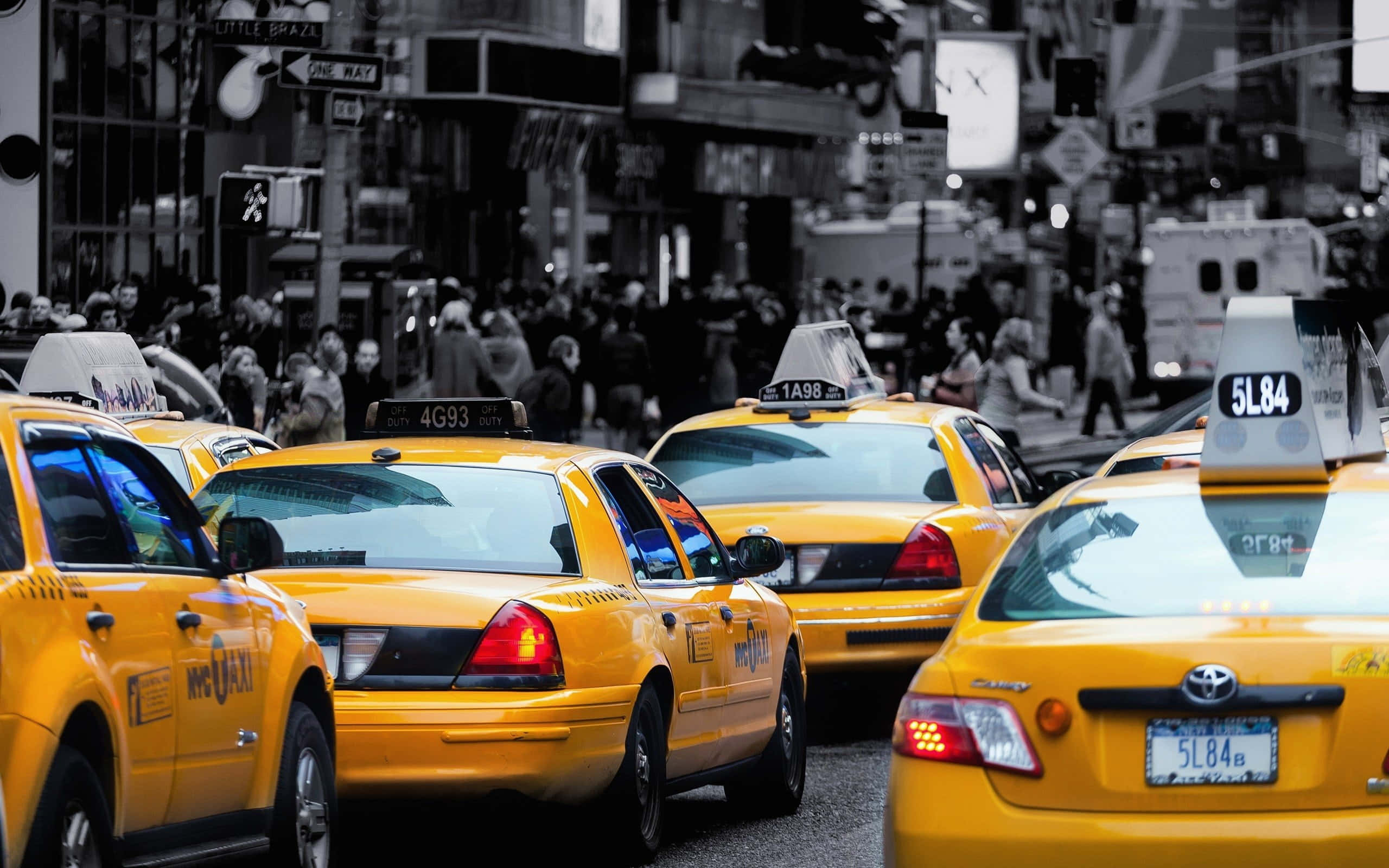 Yellow Cab 桌布 壁紙 — 鮮黃色的計程車排列在繁忙的紐約市街道上，背景有行人和城市建築。